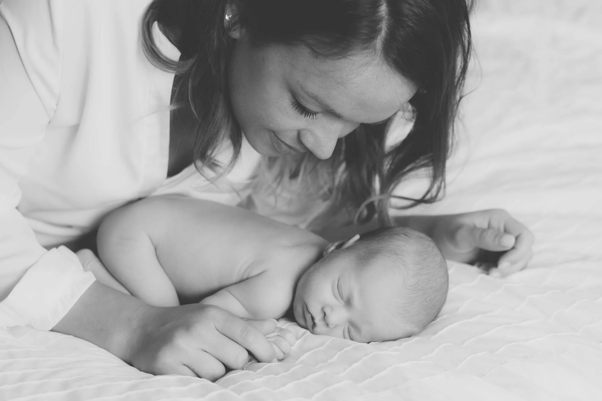 Zwarte en witte foto van een vrouw die haar baby vasthoudt, liefdevol en teder.