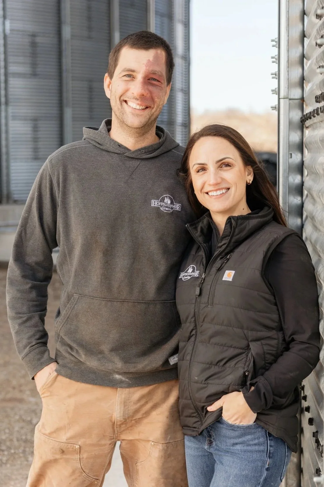Nick and Michelle Hoffsuemmer standing together beside a grain bin