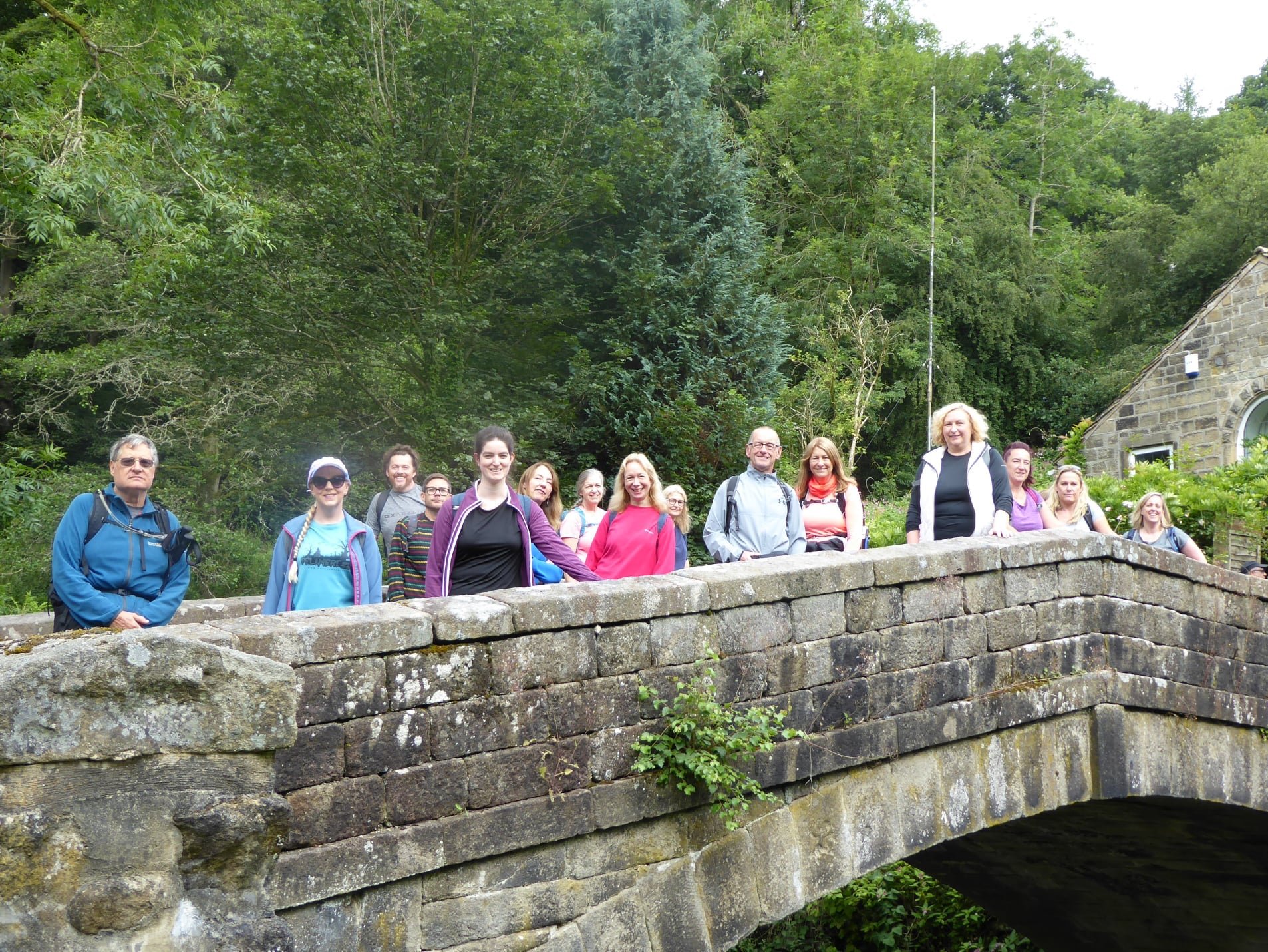 Group of people standing on a stone bridge amidst greenery