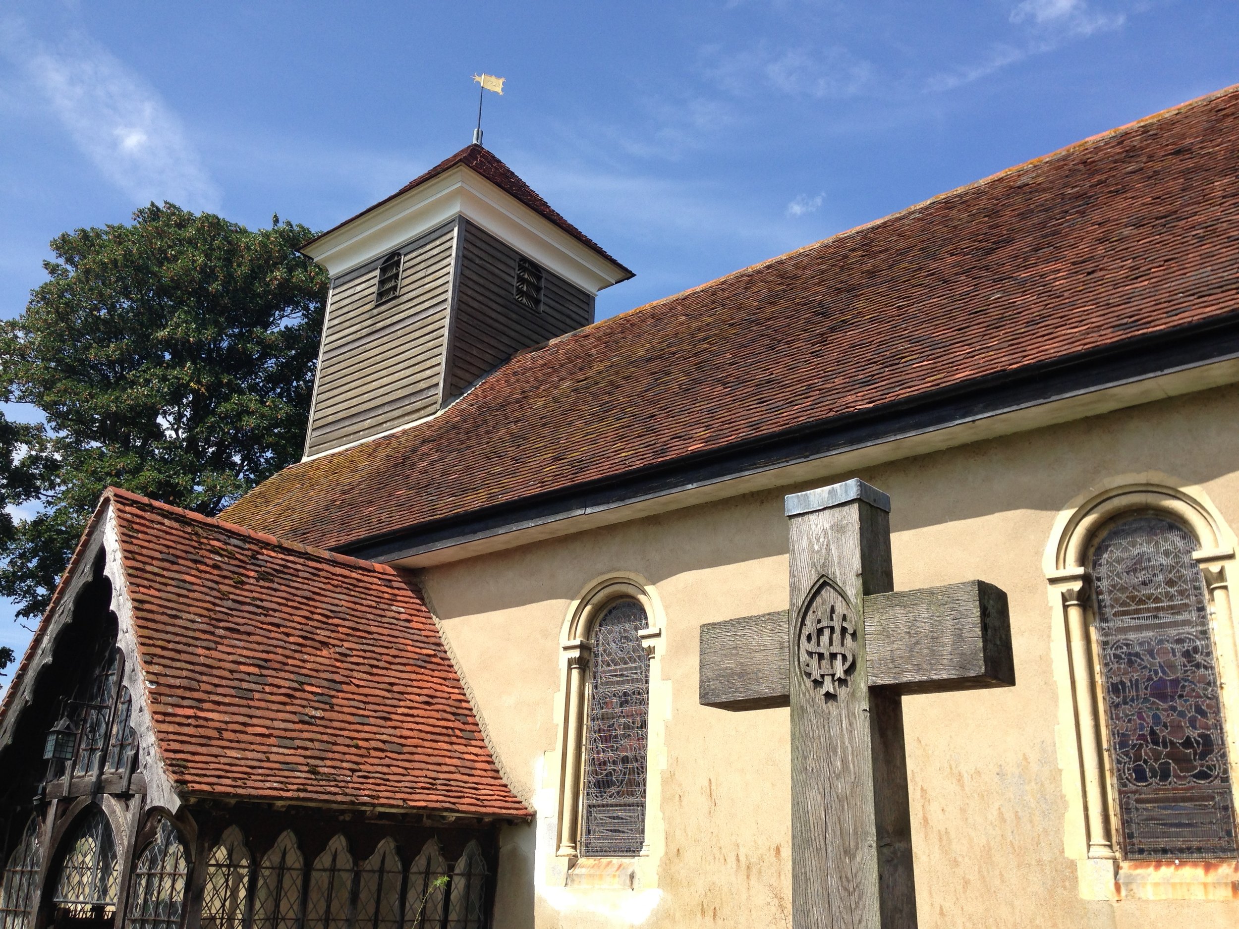 Old church building with stone cross, arched windows, and tiled roof