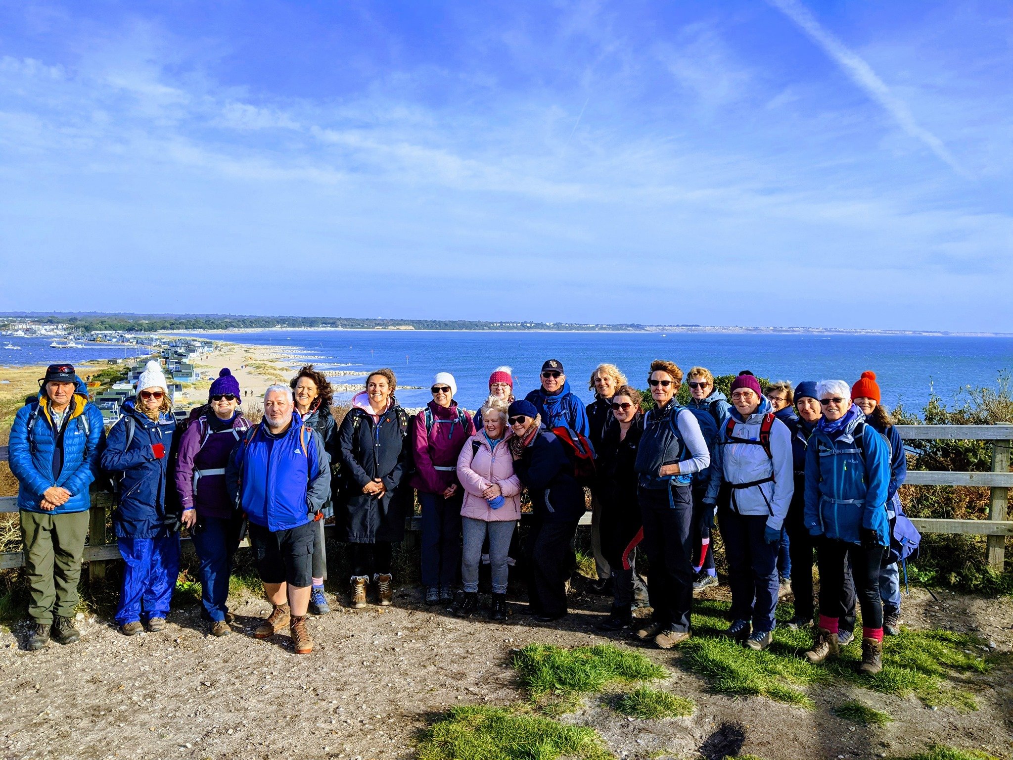 Group of people posing near a scenic seaside location with coastline and ocean view under a blue sky.