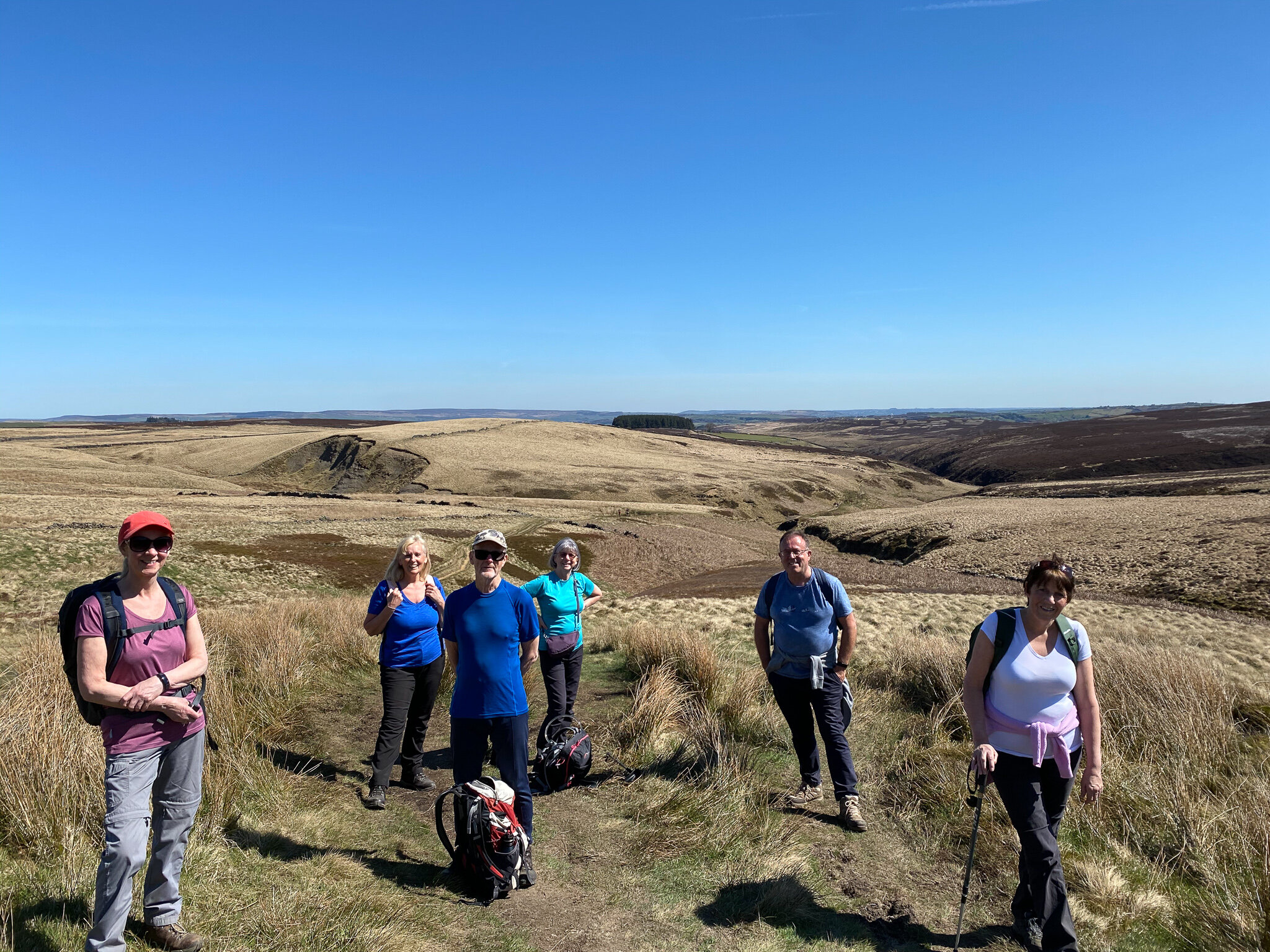 Group of hikers standing on a grassy trail in open countryside