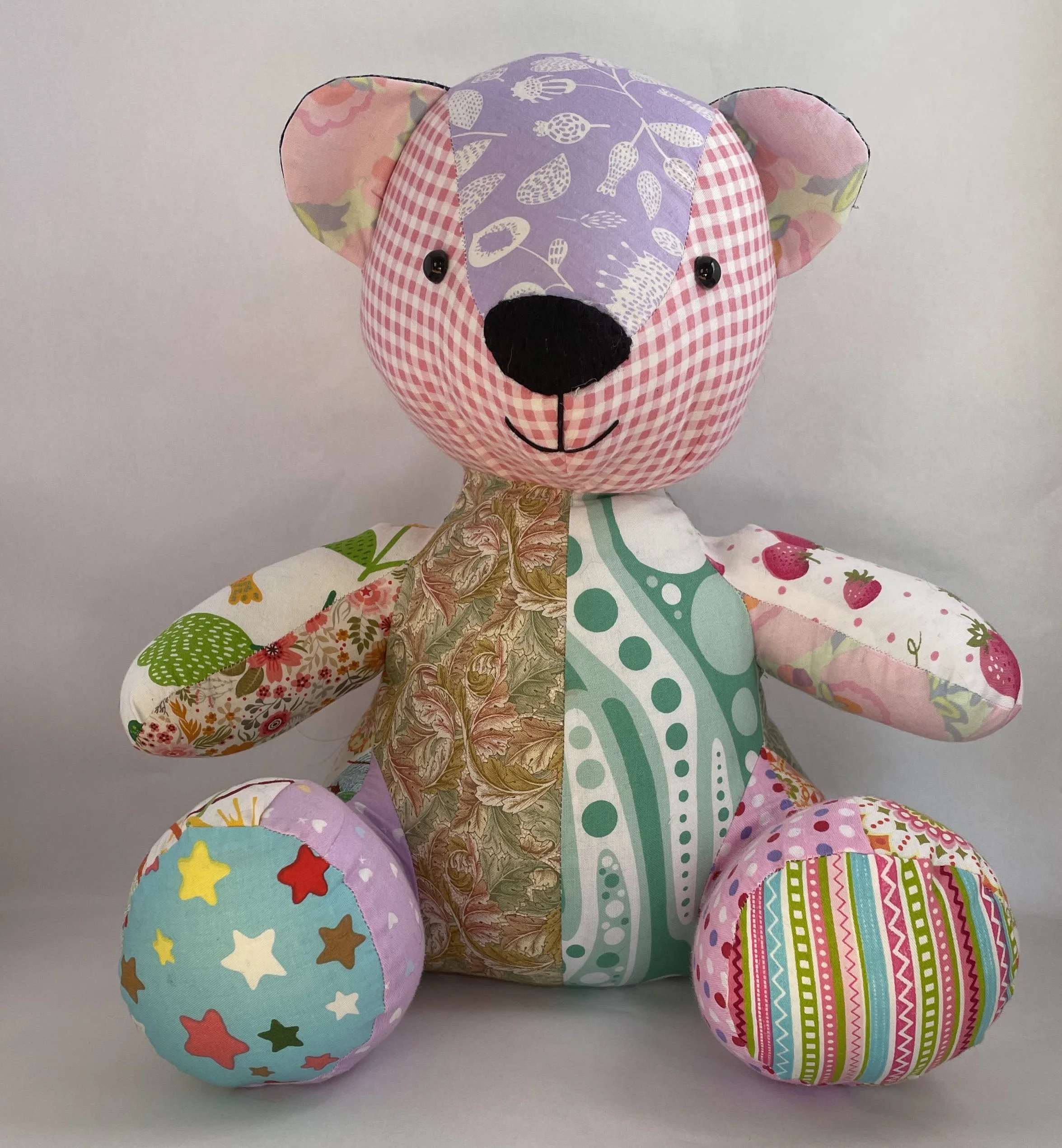 Large teddy bear made of assorted pink fabric