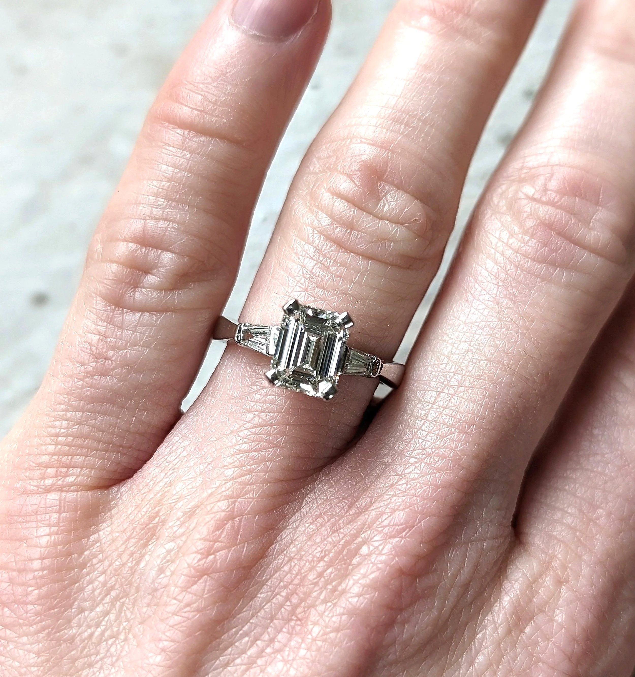 Platinum diamond ring with one center emerald cut diamond weighing 2.03ct and 2 tapered baguette diamonds weighing 0.40ctw. Size 6.25. (100-401)