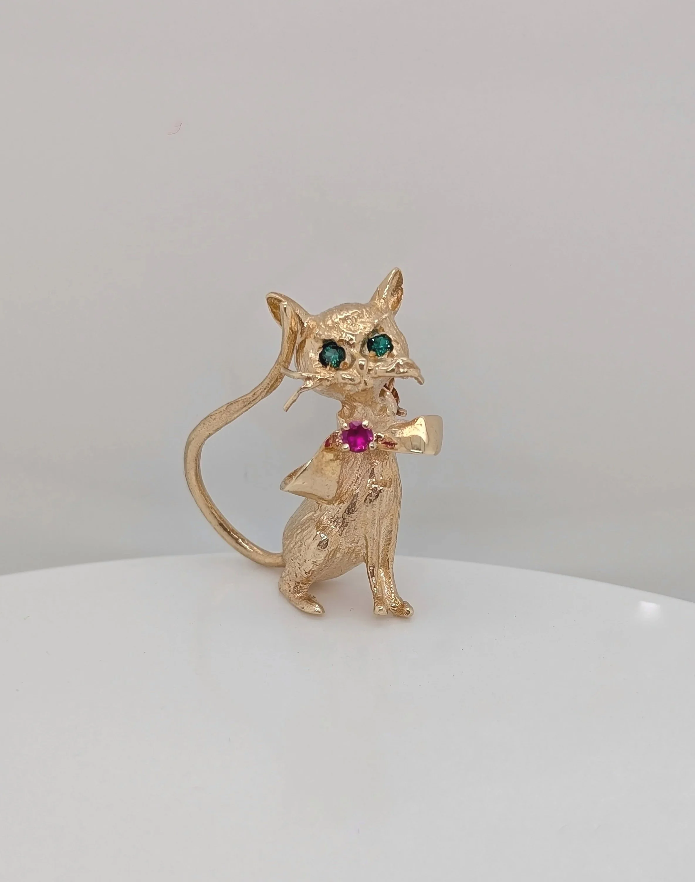 14k yellow gold cat brooch with lab grown ruby bow and lab grown emerald eyes. (250-706)