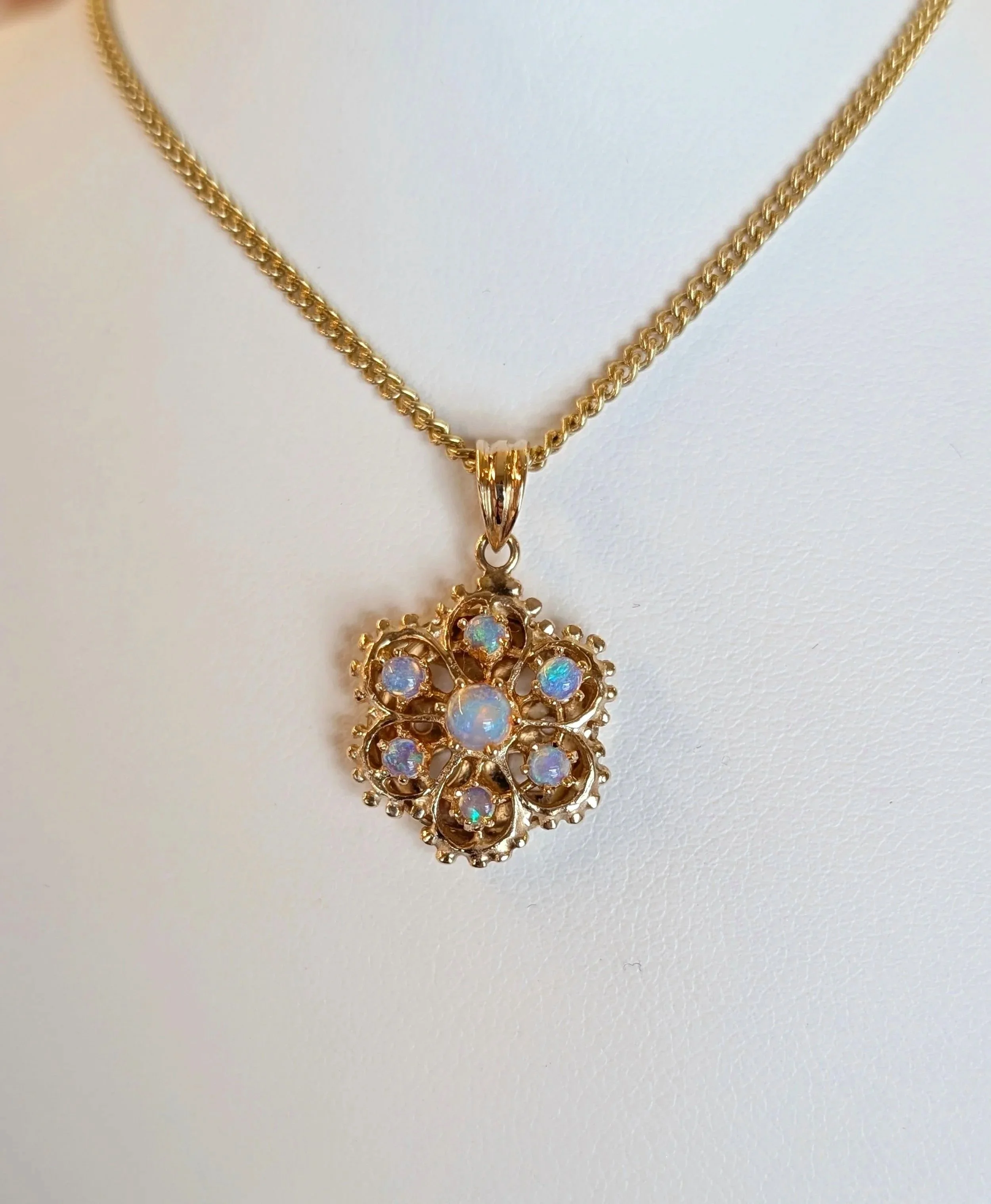 14k yellow gold floral motif opal pendant on an 18k yellow gold curb chain. (230-1685)