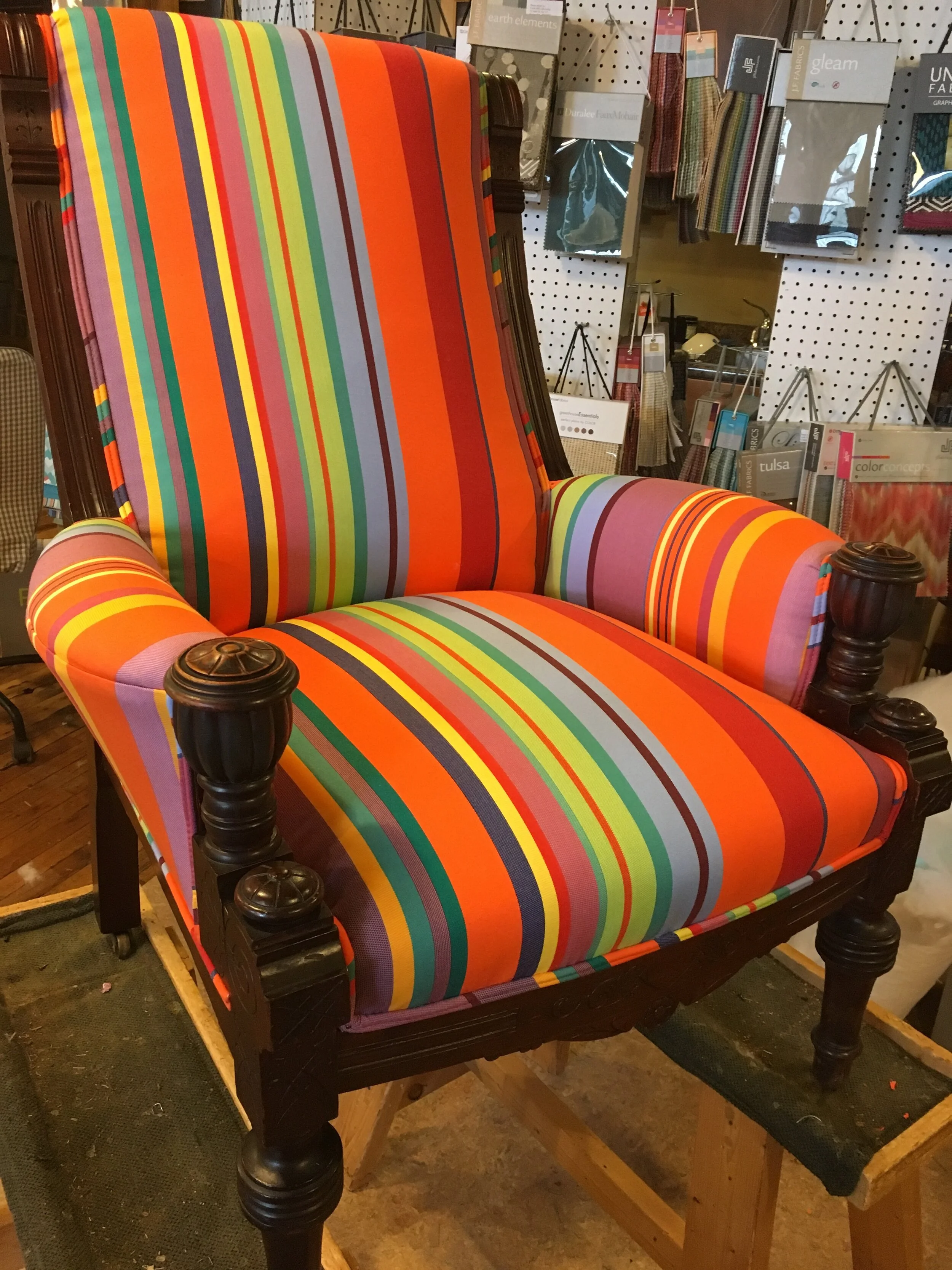 Colorful striped armchair with wooden details in a fabric store display.