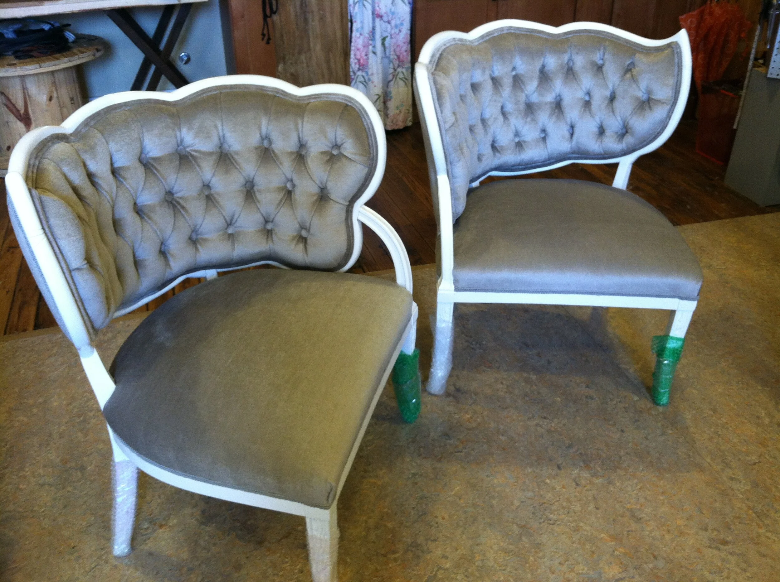 Two elegant chairs with tufted backs and gray cushions on a wooden floor.