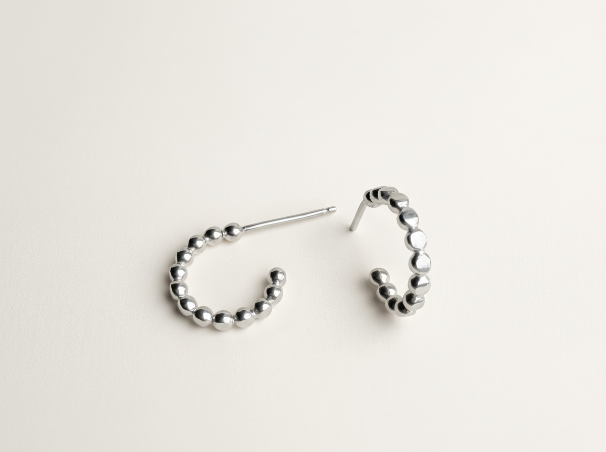 Side view of small sterling silver dot hoop earrings