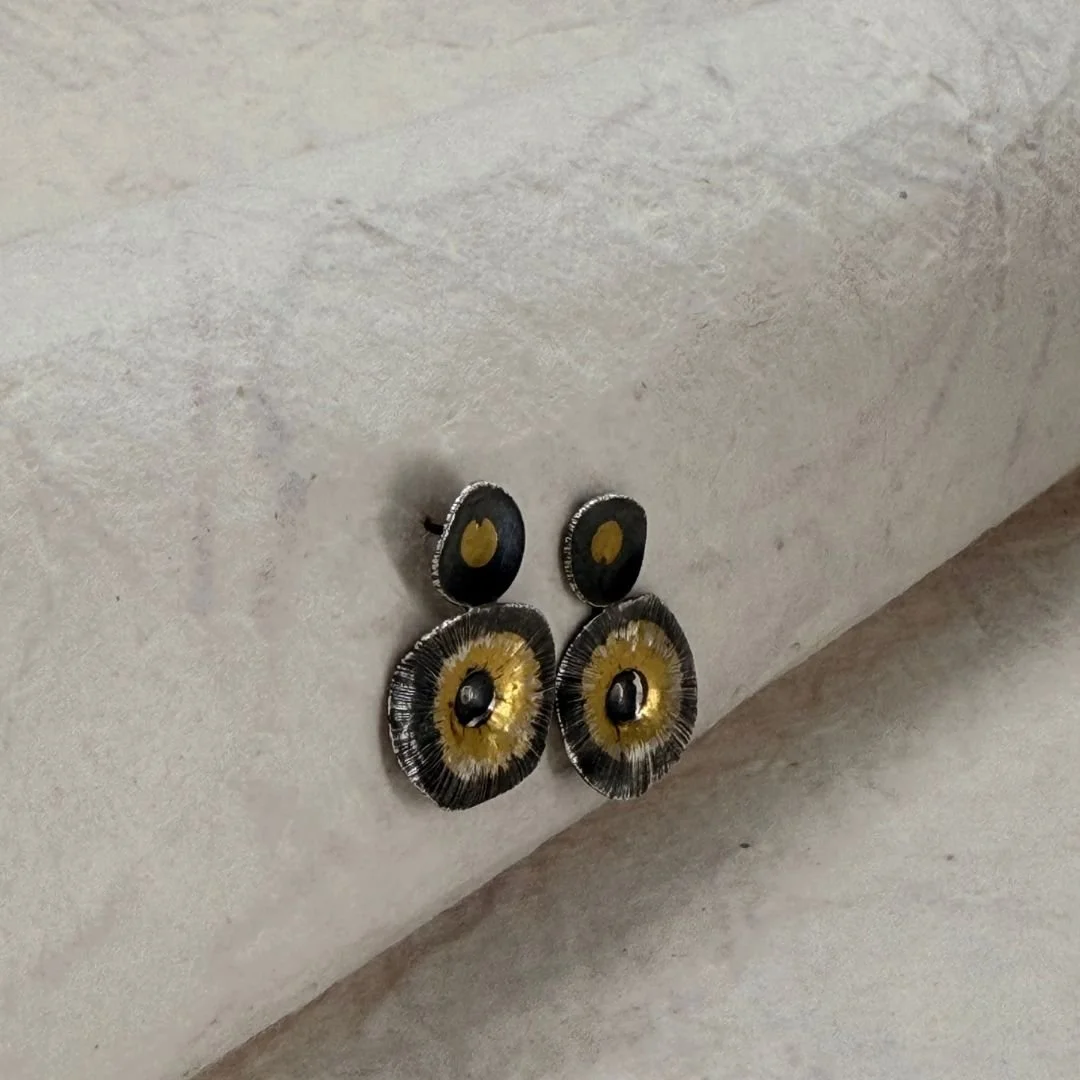 Pair of Echo Earrings resting against pale stone, showing their overall size and shape