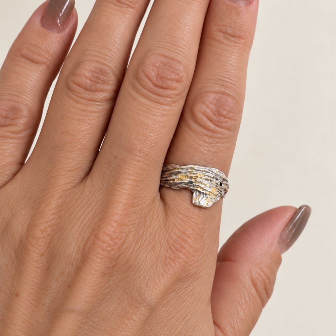 Bark Ring worn on a finger, showing its textured silver surface and small gold accents.