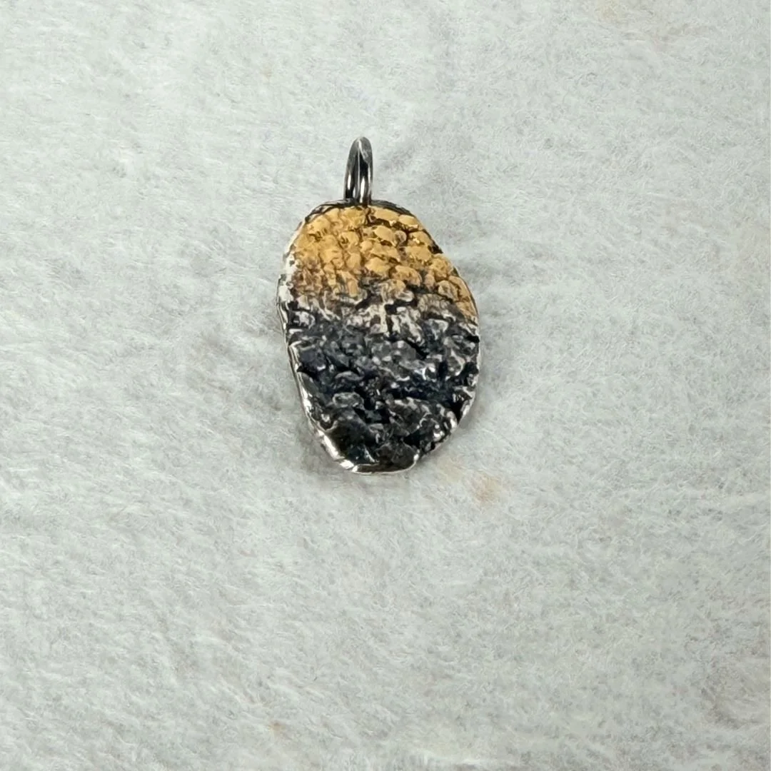 Close-up of the keum-boo gold detail on the oxidized sterling silver oval pendant. The gold transitions gradually from the top edge into the dark oxidized silver below.