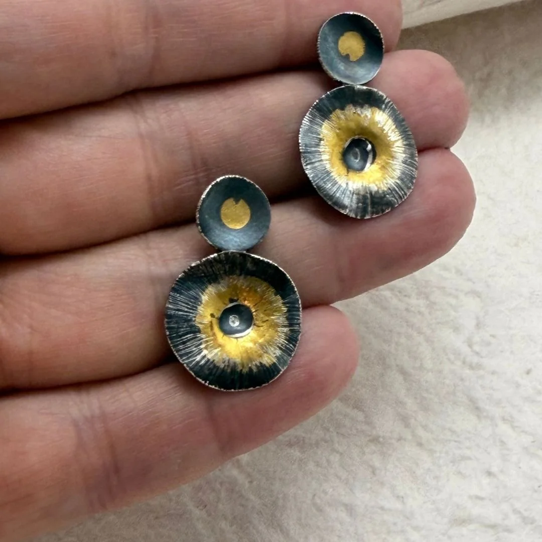 Echo Earrings held in a hand to show their scale and textured surfaces
