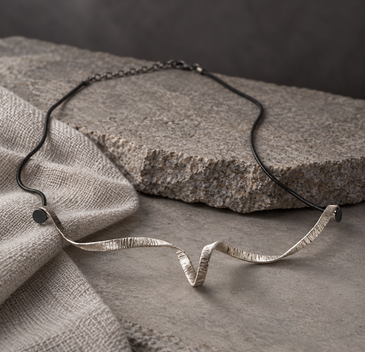 Full Spiral Unfolded Necklace on gray stone, showing the oxidized silver snake chain, clasp, and extension chain.