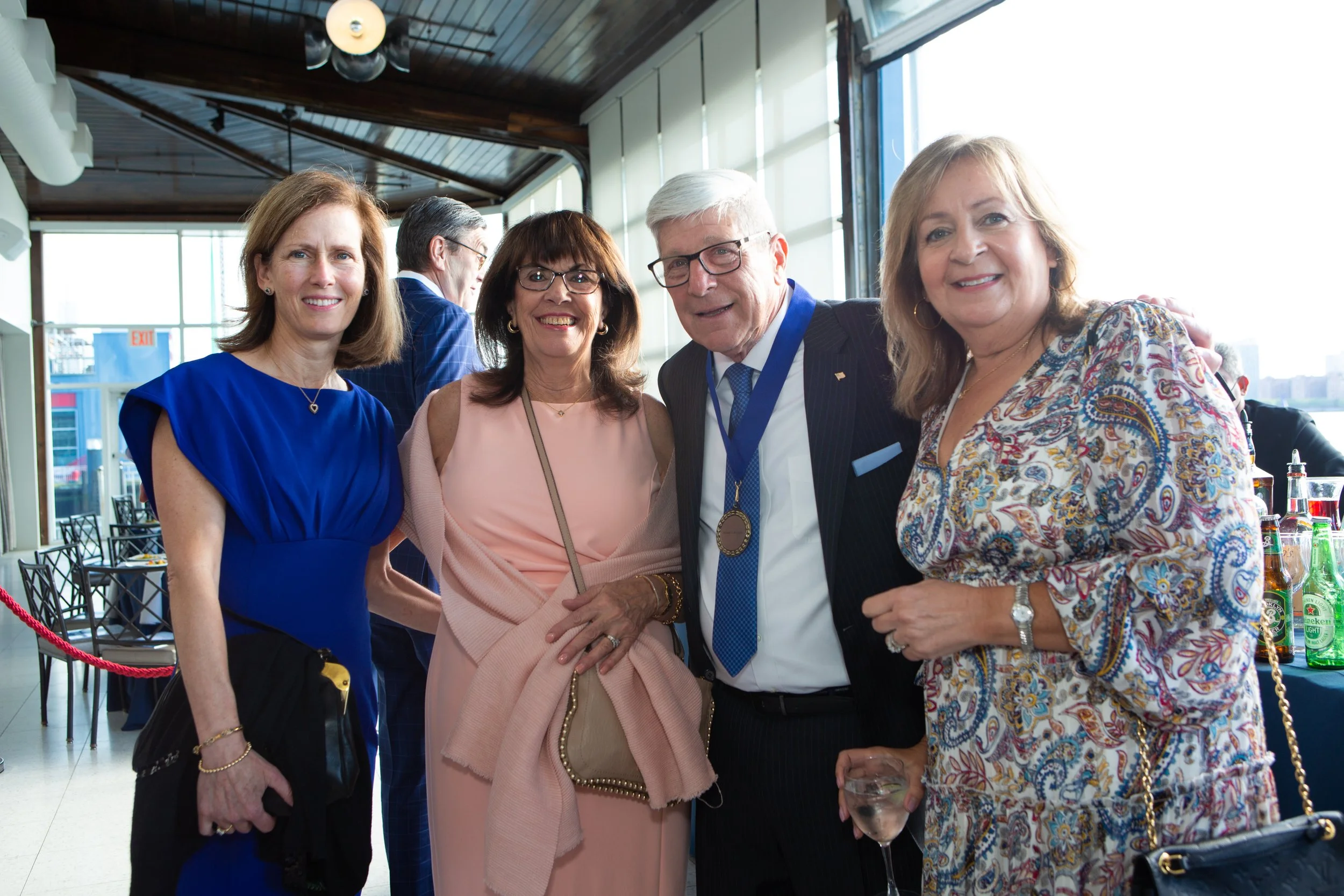 Group of four adults smiling at a formal event, with a man wearing a medal.
