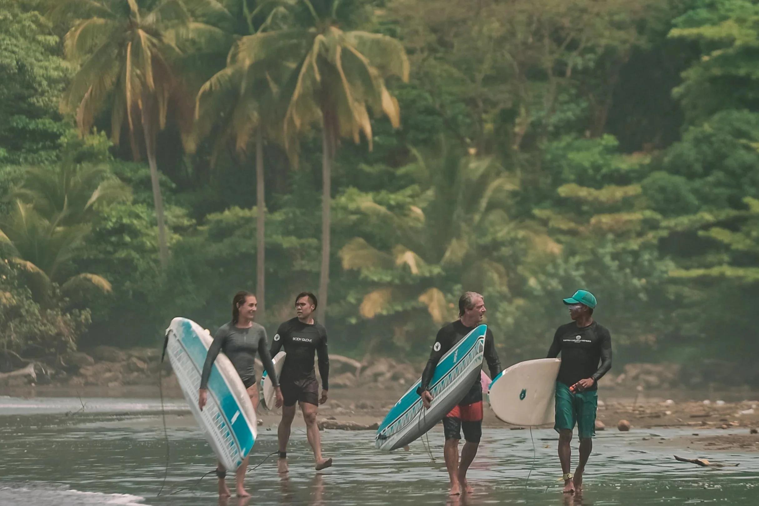 Four Surfers walking Estero Beach with their surfboards