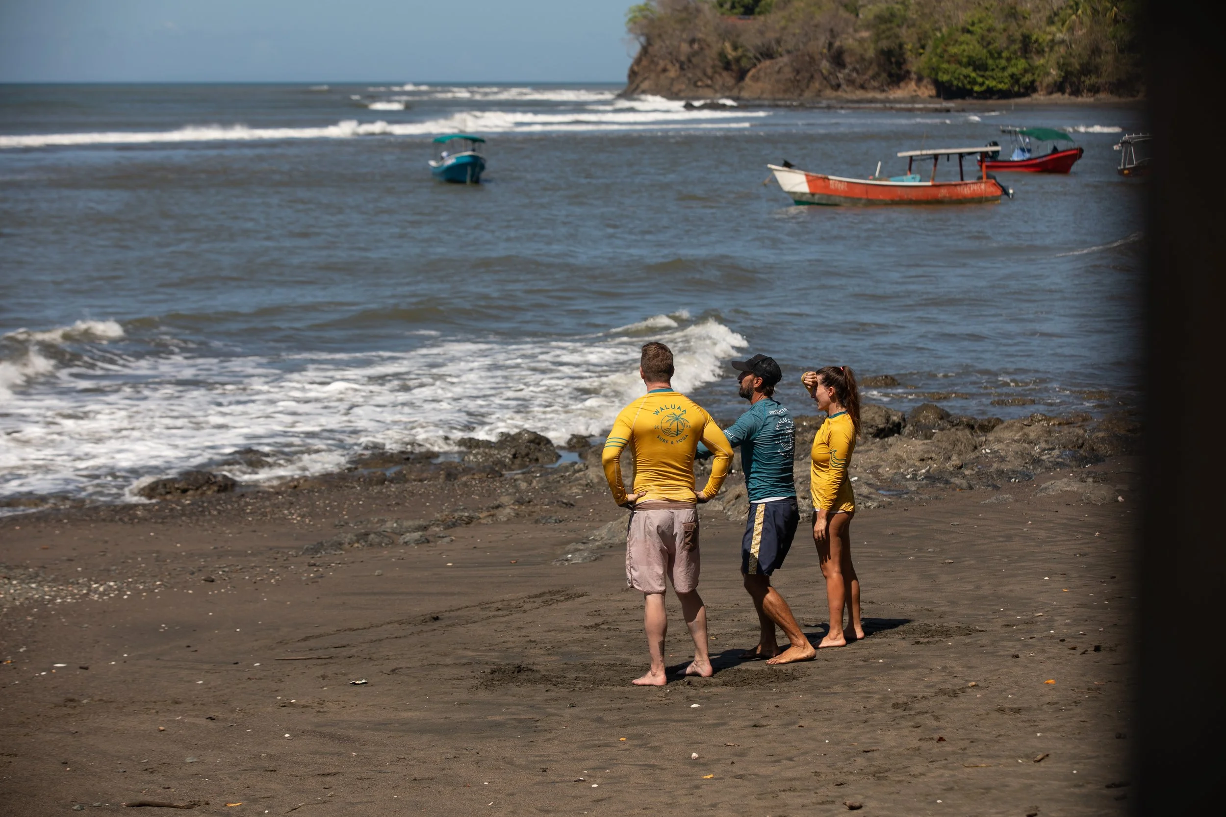 Two guests and an instructor watching waves at Town Beach