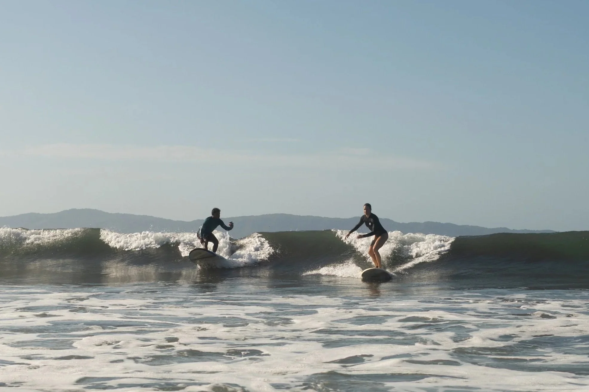 waluaa guest riding a wave with surf instructor filming her progress