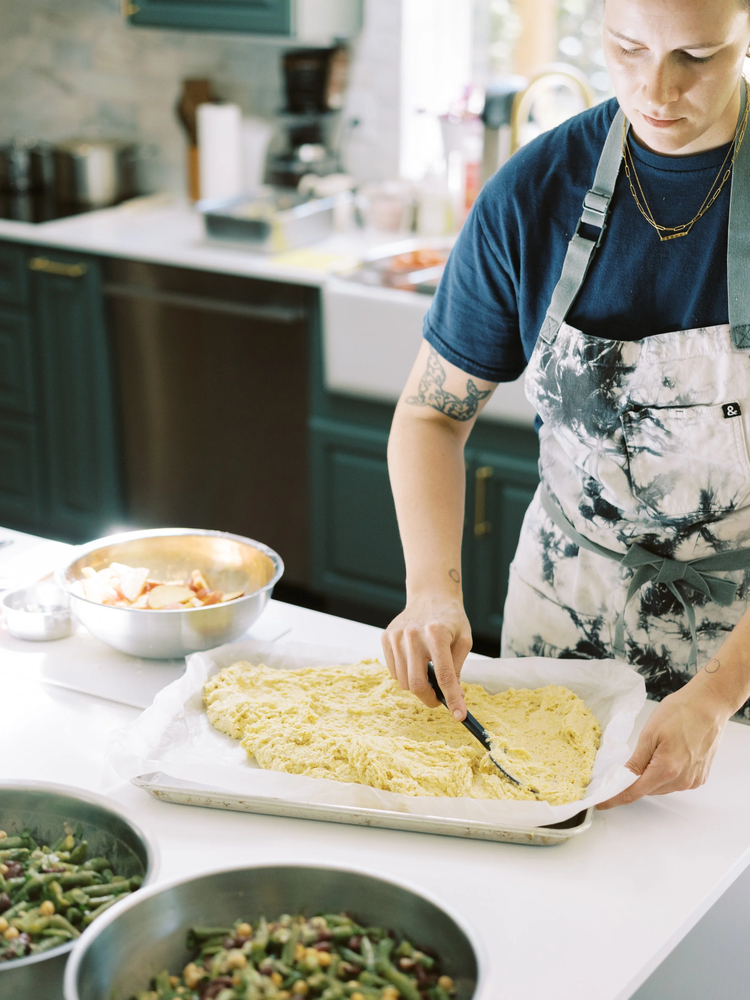 Private chef slicing a freshly prepared baked dish in a bright residential kitchen.