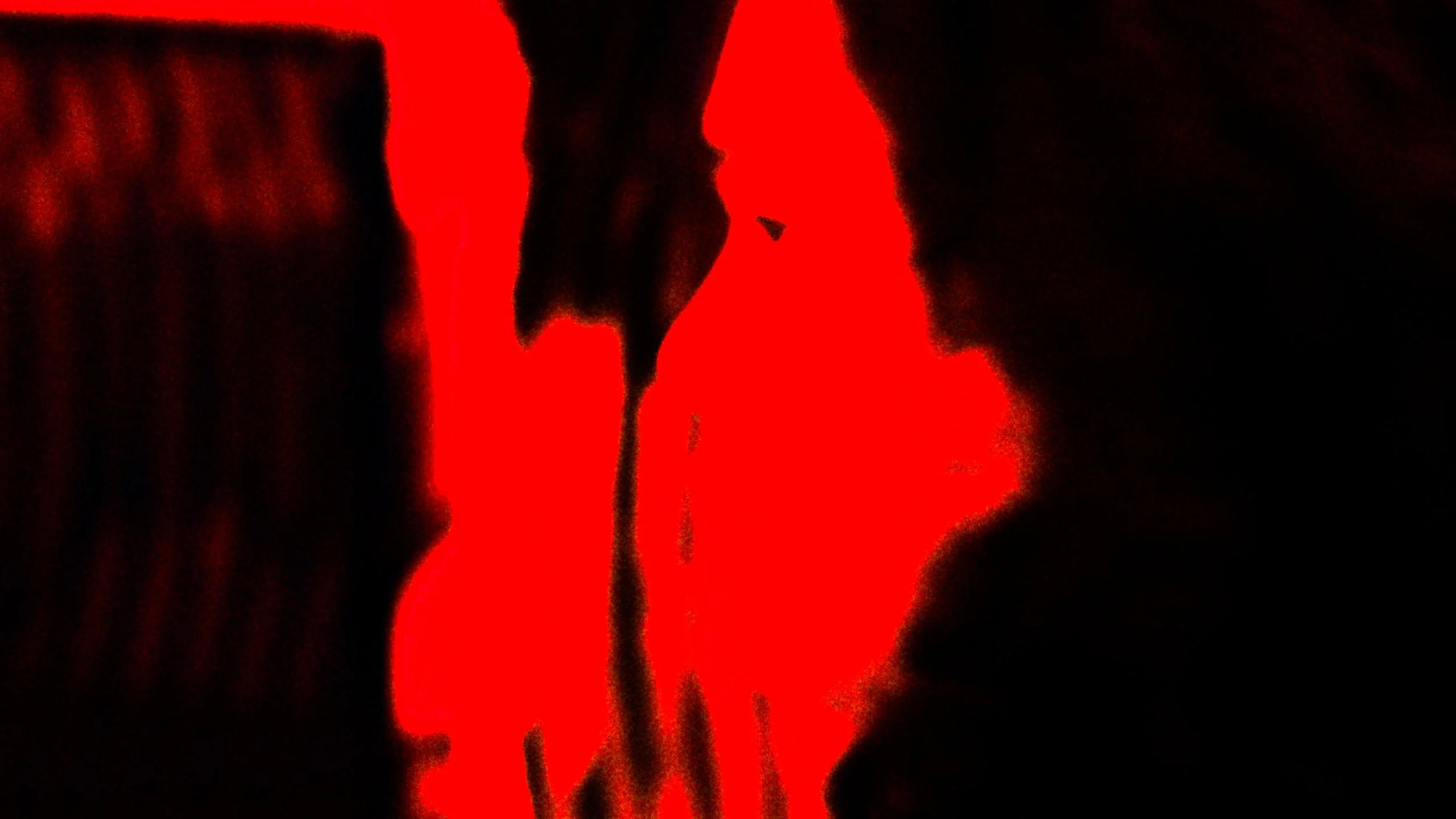 Silhouette of a person illuminated by red light, with a dark background.
