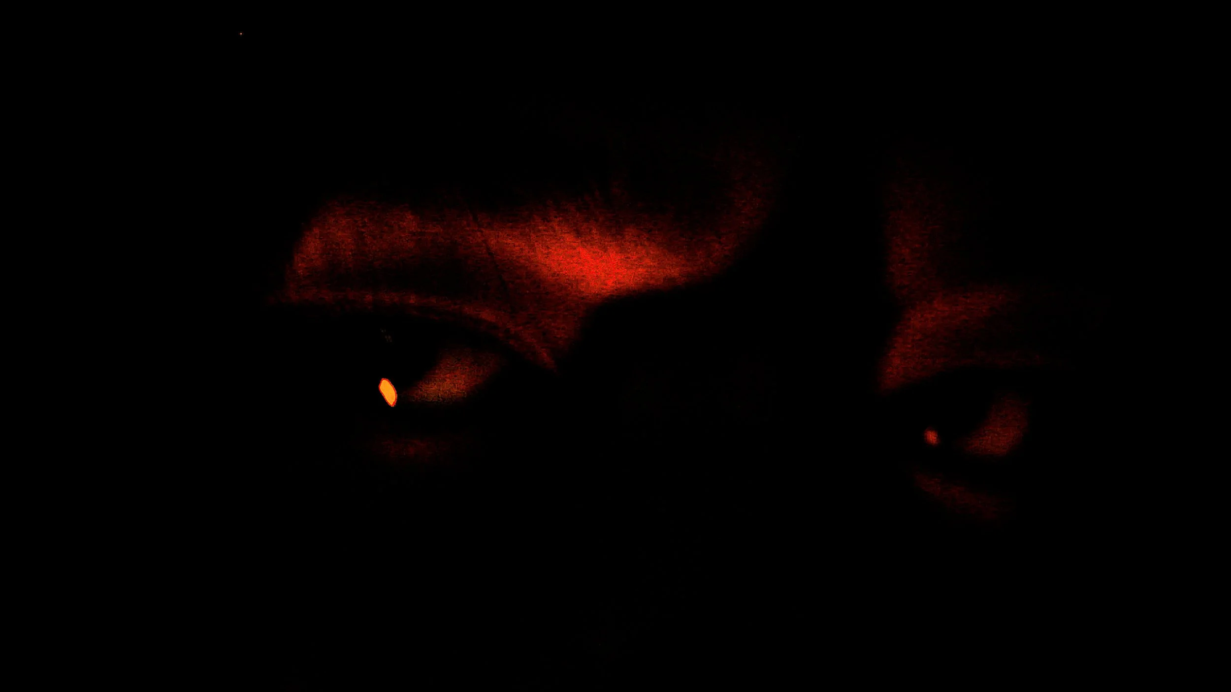 Dark image with faint red lights and a small orange light in a mostly black background.