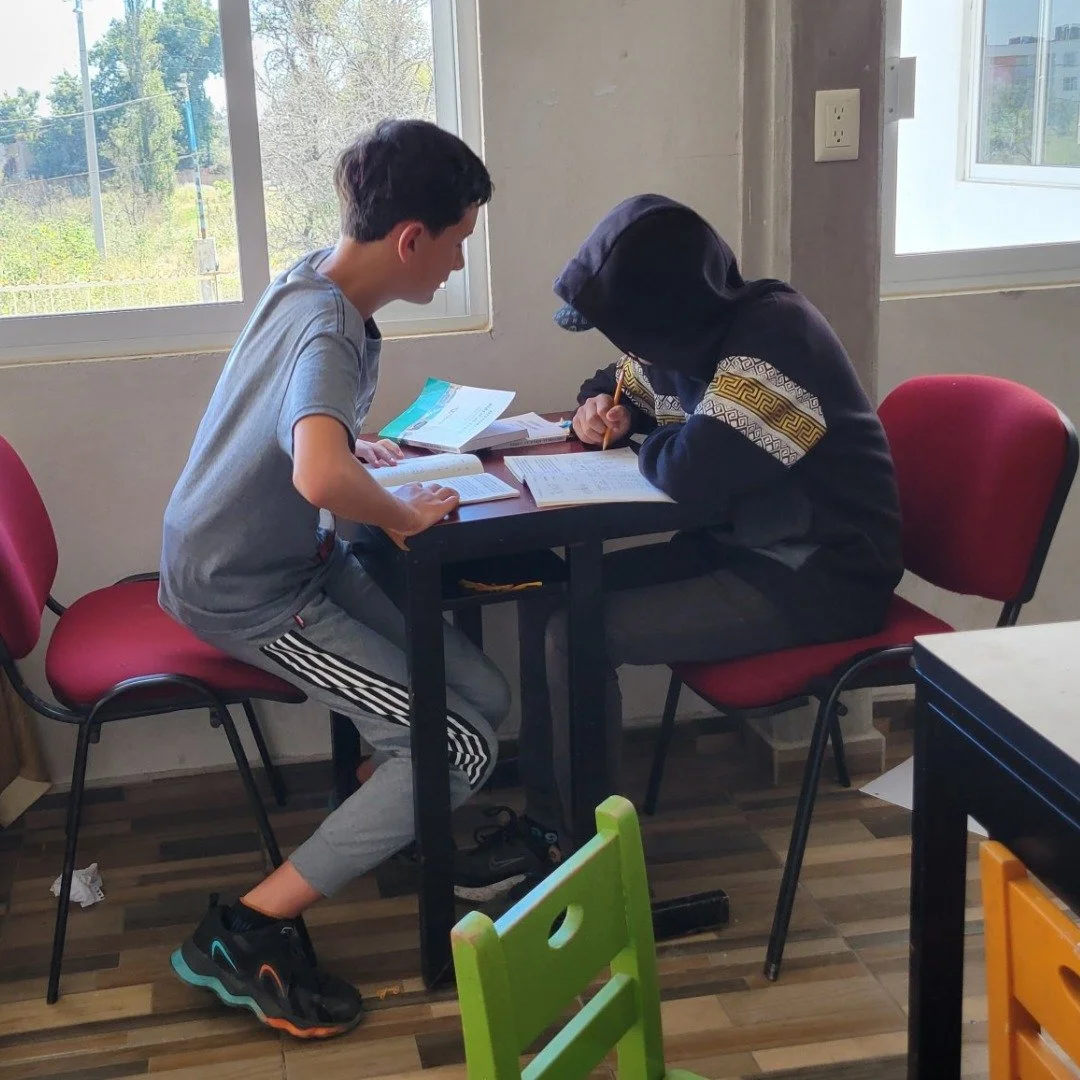 One thirteen year old helping another thirteen year old learn to read in our school
