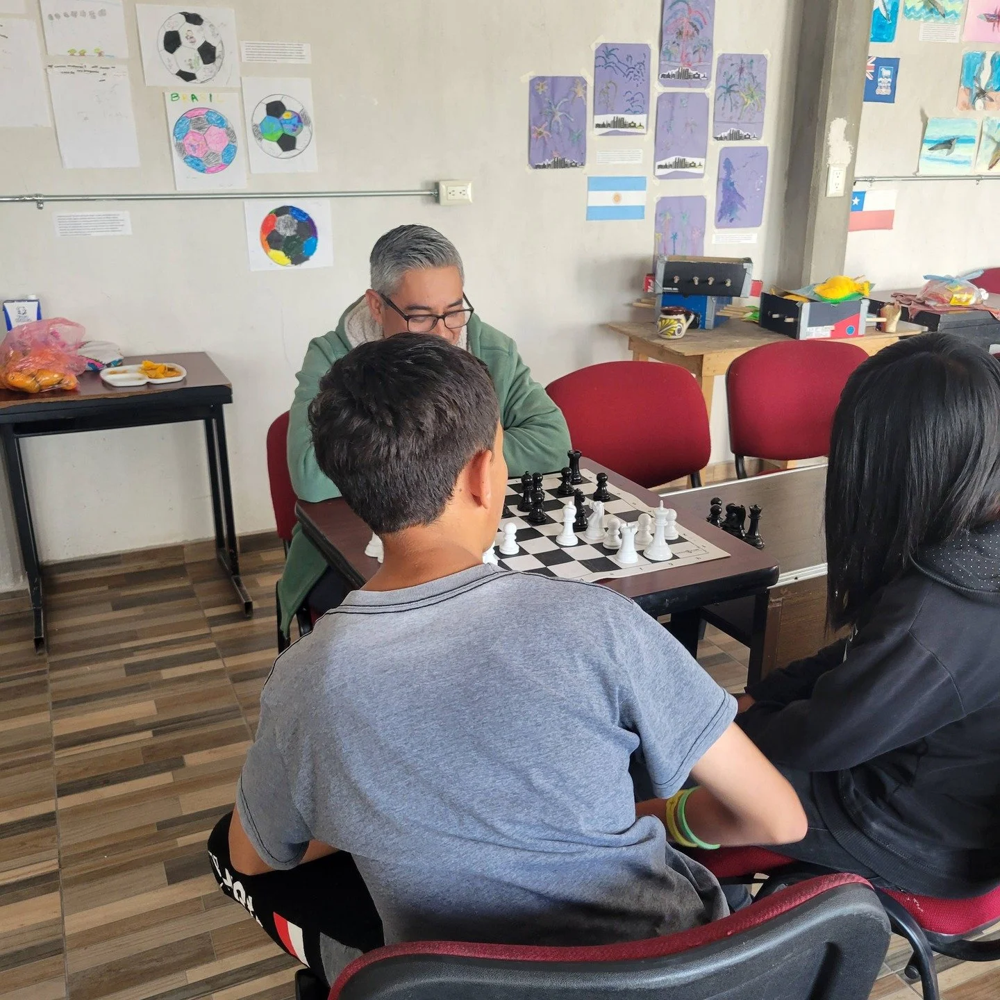 Recess at school - one bunch playing with Legos while two other play chess with Teacher Abraham.
