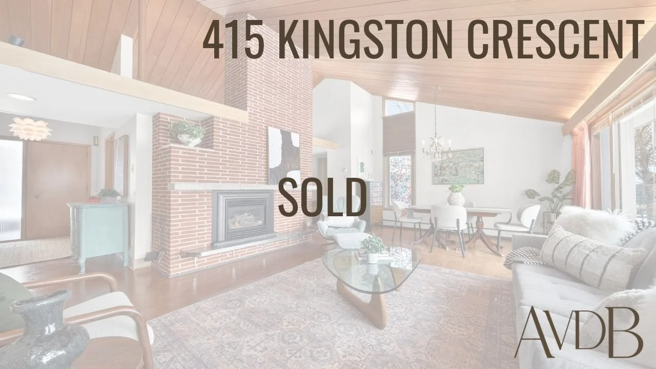 Bright living room with brick fireplace, wooden ceiling, and large windows with curtains