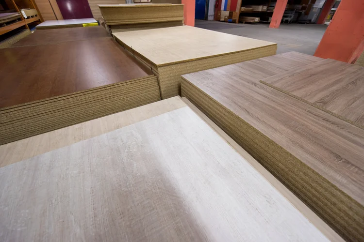 Laminated boards in woodgrain and plain finishes stacked in a factory