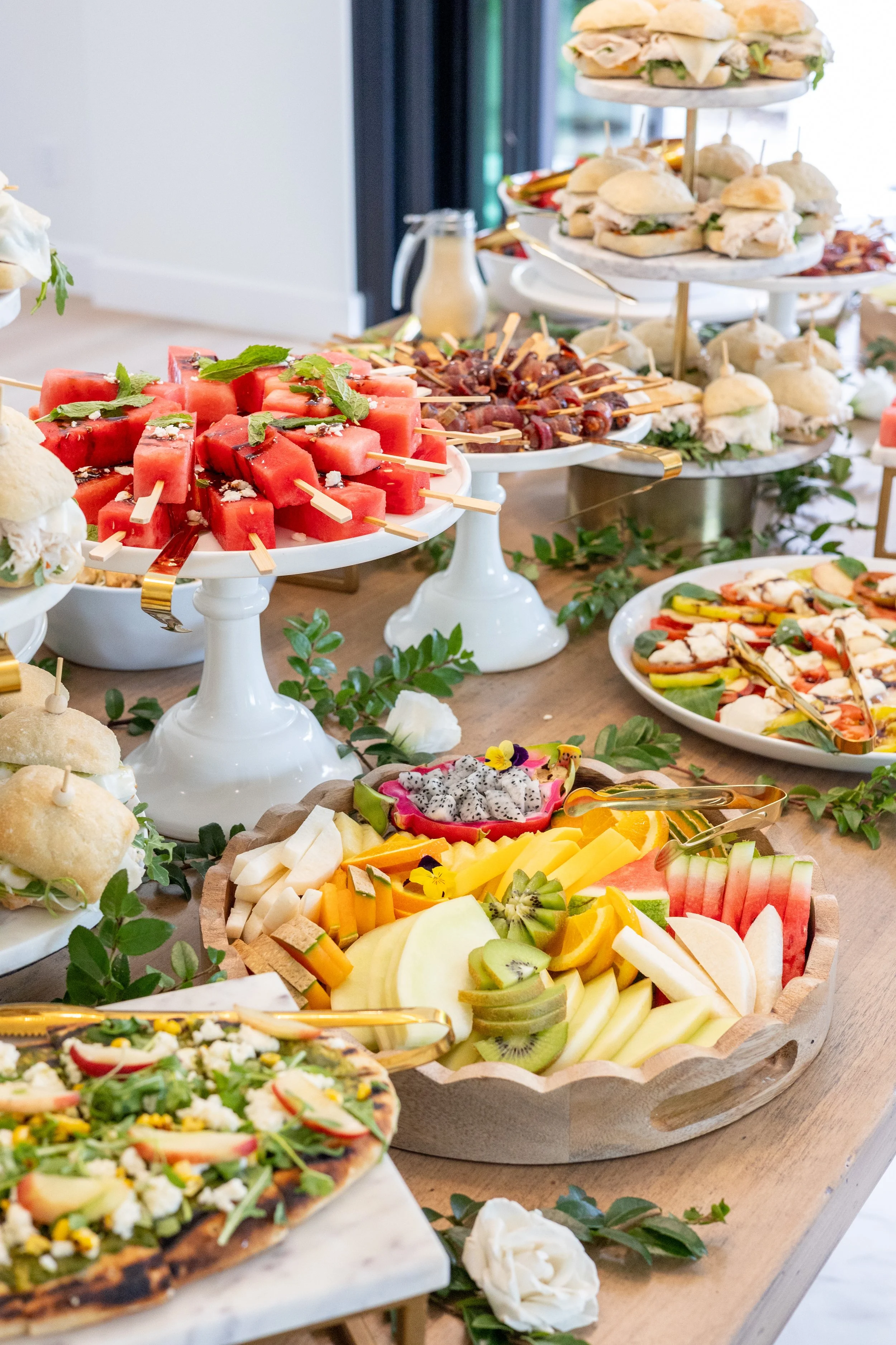 Grazing table catering display with fruit, sandwiches, and appetizers by Taylor Made Cuisine