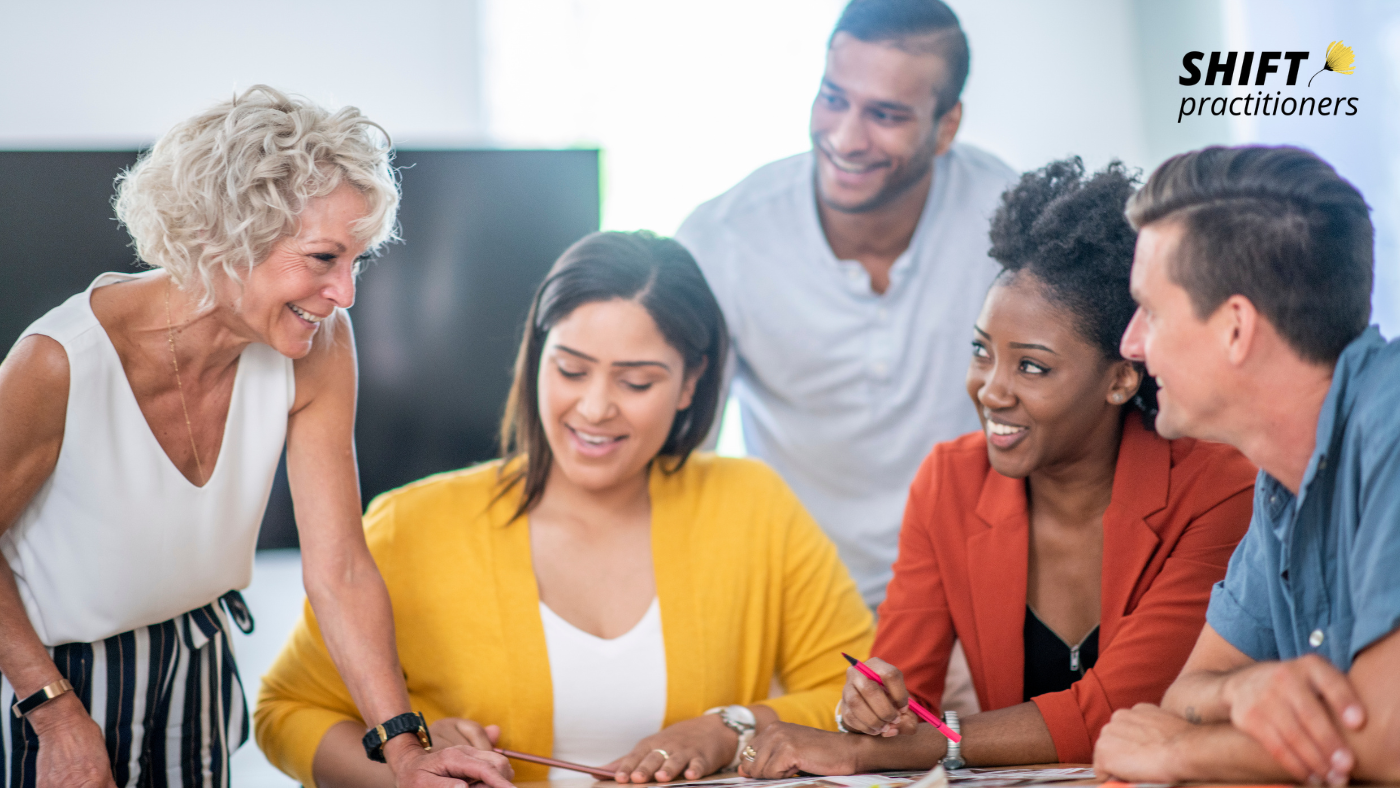 Diverse team of professionals collaborating around a table, illustrating human-centred leadership, inclusion and teamwork in the future of work.