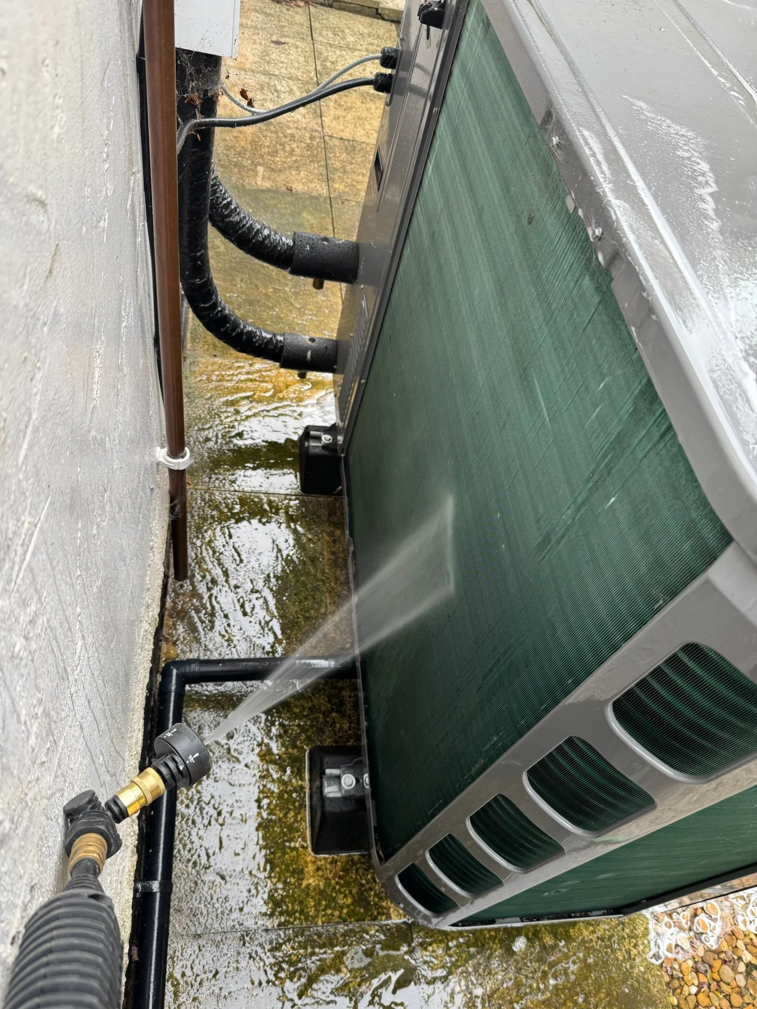 A heat pump getting jet washed as part of a heat pump service