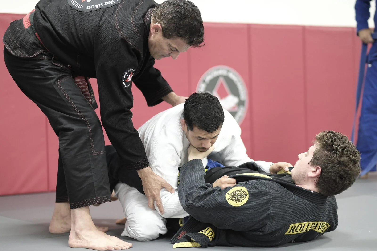 An instructor teaching a technique to students on the mat at a jiu-jitsu academy