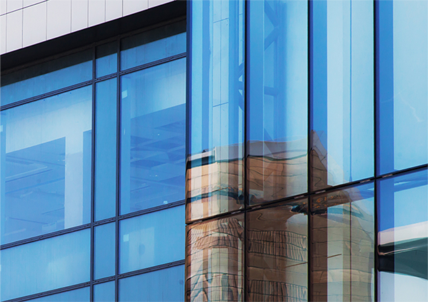 Modern glass building with reflections of another structure