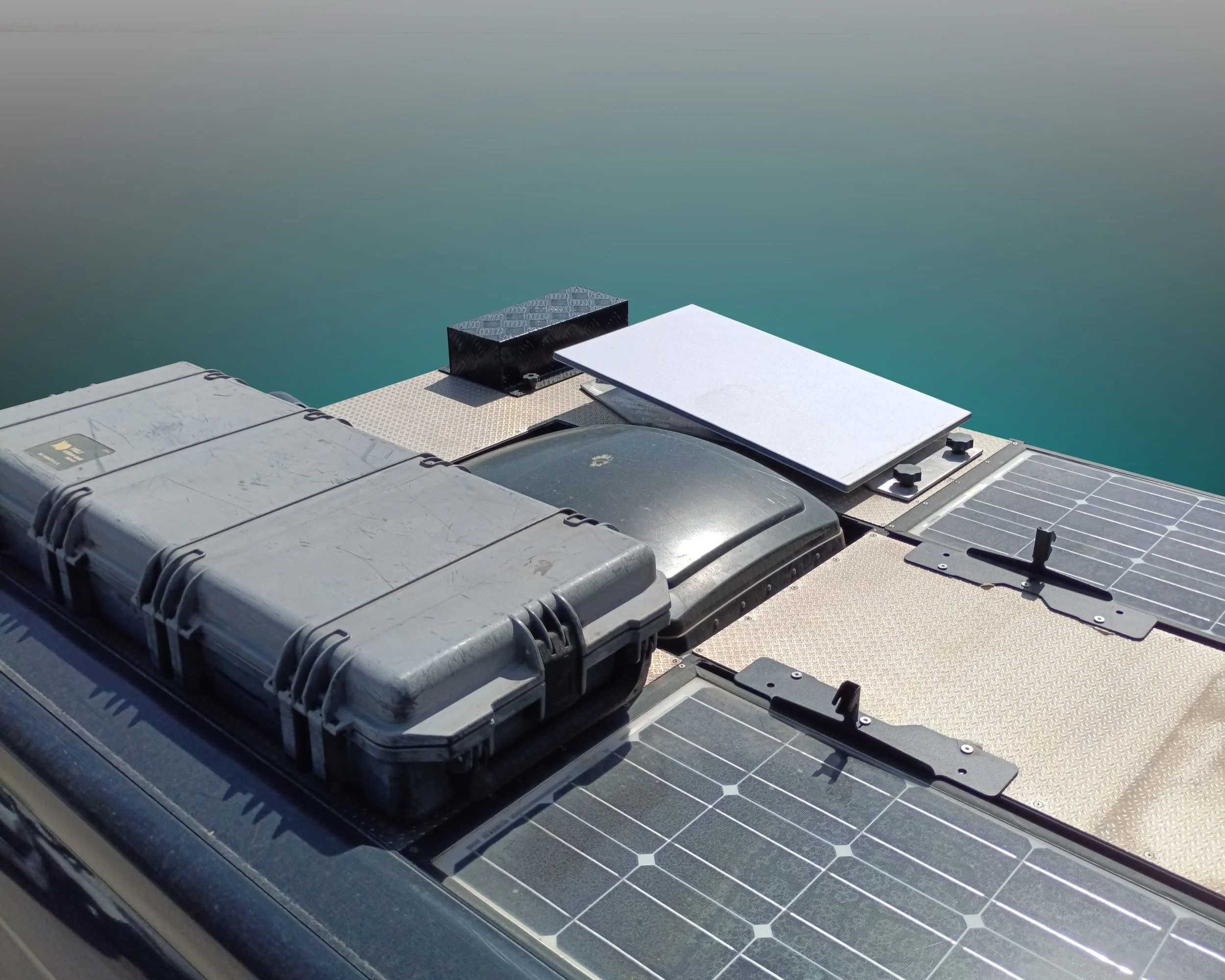 Componenti di un sistema di pannelli solari installati su una superficie, con un contenitore grigio, pannelli solari e altri dispositivi elettronici