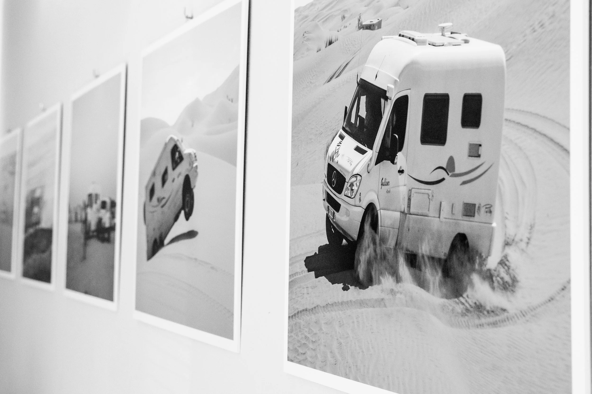 Fotografia in bianco e nero di un camper che attraversa la neve in un paesaggio desertico.