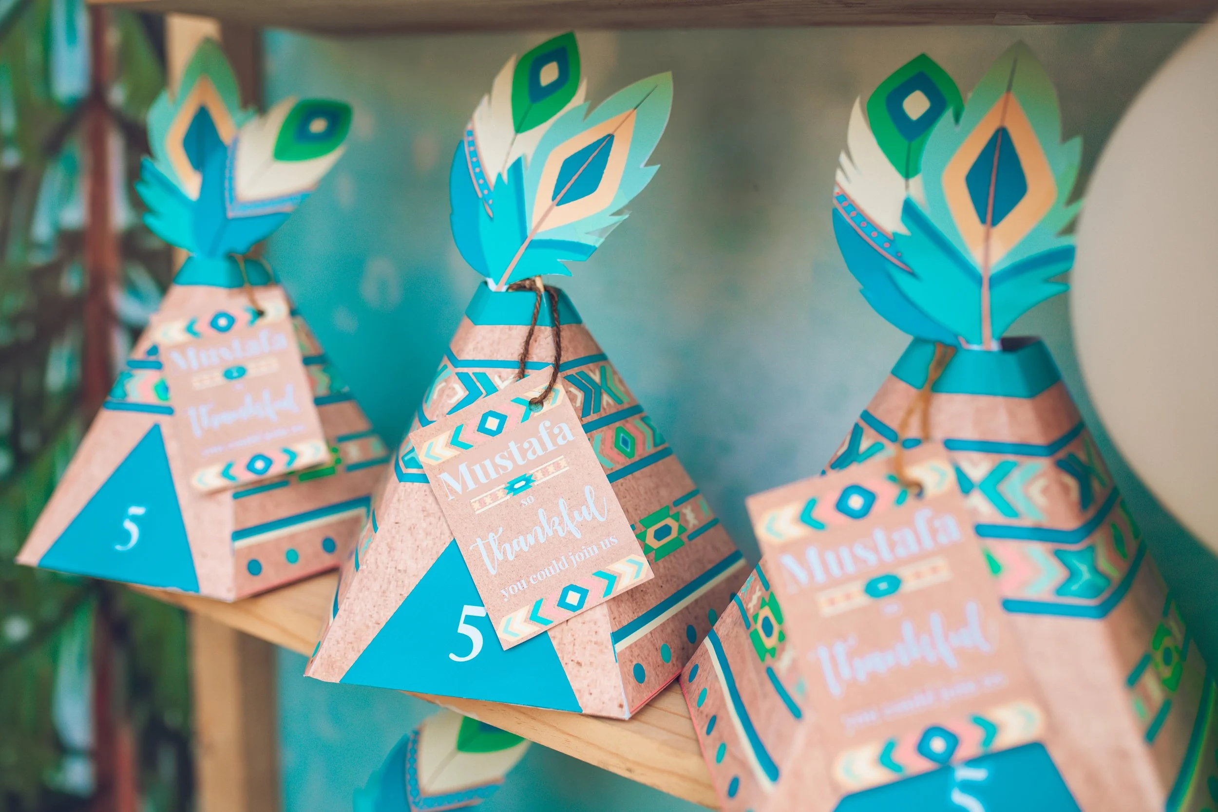 Decorative pyramid-shaped party favors with colorful feathers and geometric patterns