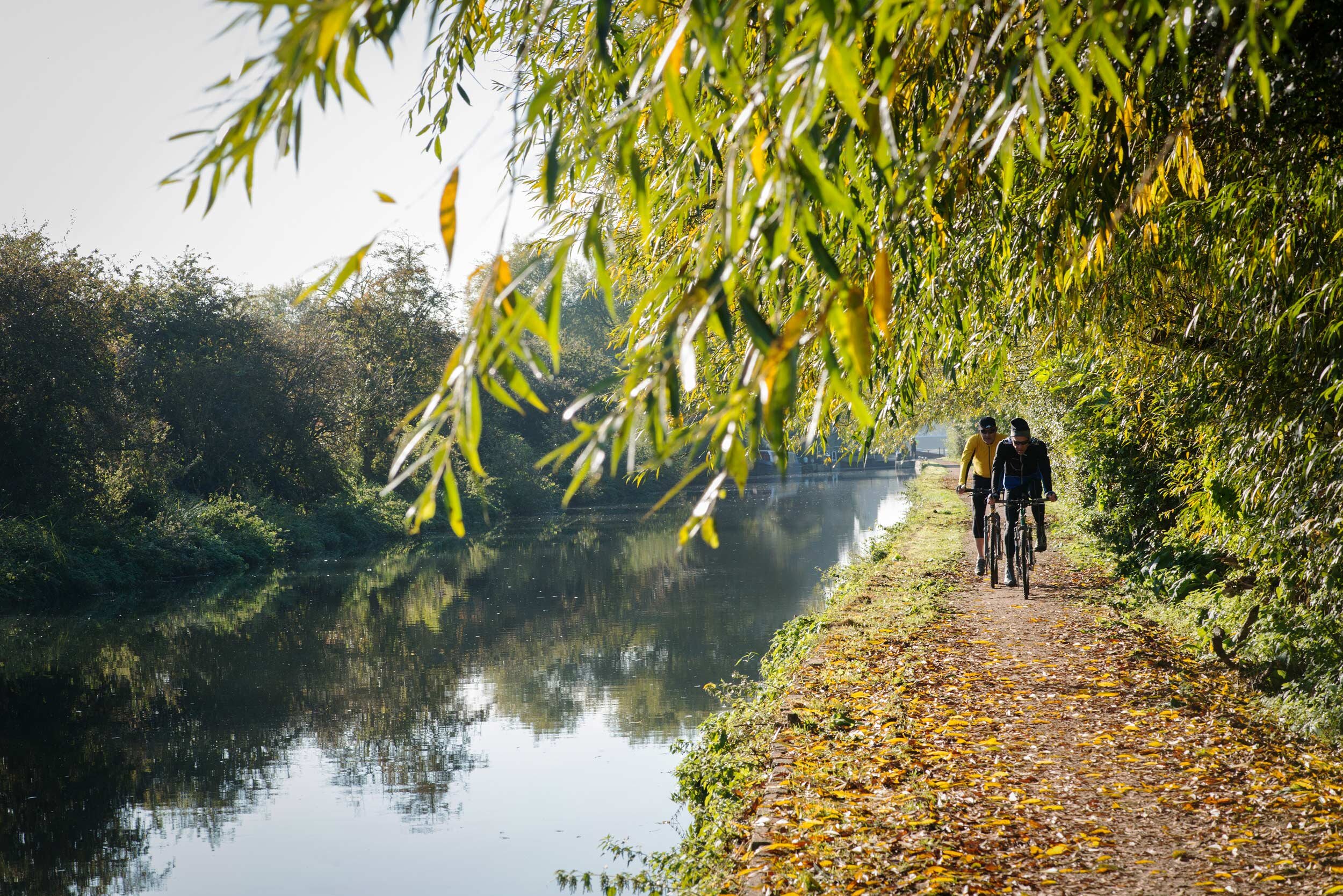   Lee Valley Park. River Lee Country Park in autumn. Cyclists on the towpath near Cheshunt.  Shot by Eleanor Bentall, photographer. 