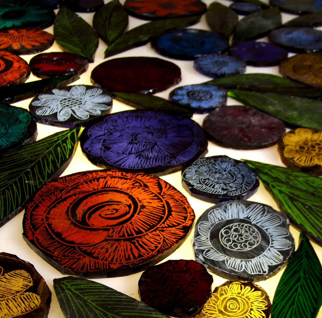 Échantillons de peinture à la grisaille sur verre présentant différents motifs, traits et effets après cuisson.