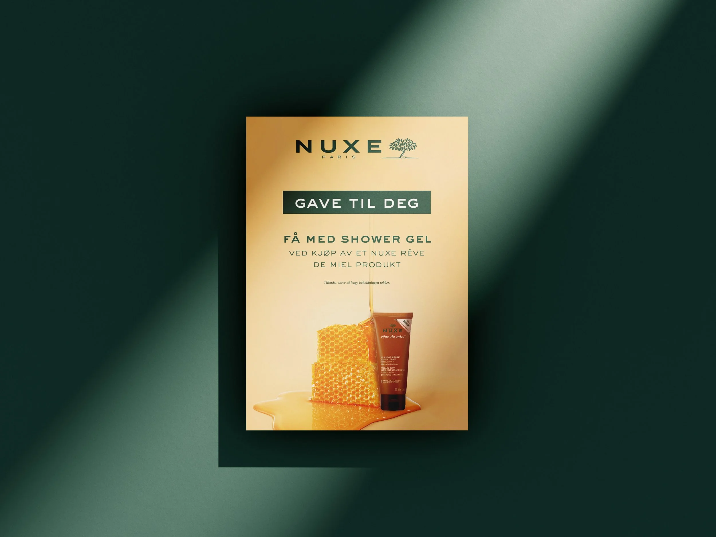 nuxe flyer med mørkegrønn tekst og lys orange bakgrunn. flyeren informerer om at du kan få med en gratis shower gel ved kjøp av et spesielt produkt