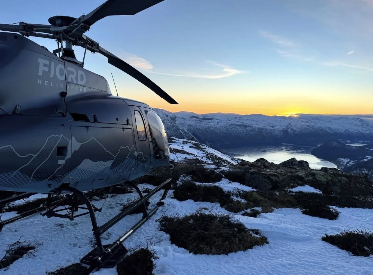 fjord helikopter logo med profilering og folieringsdesign på. helikopteret har mange fjell i designet, tegnet i hvitt og blått