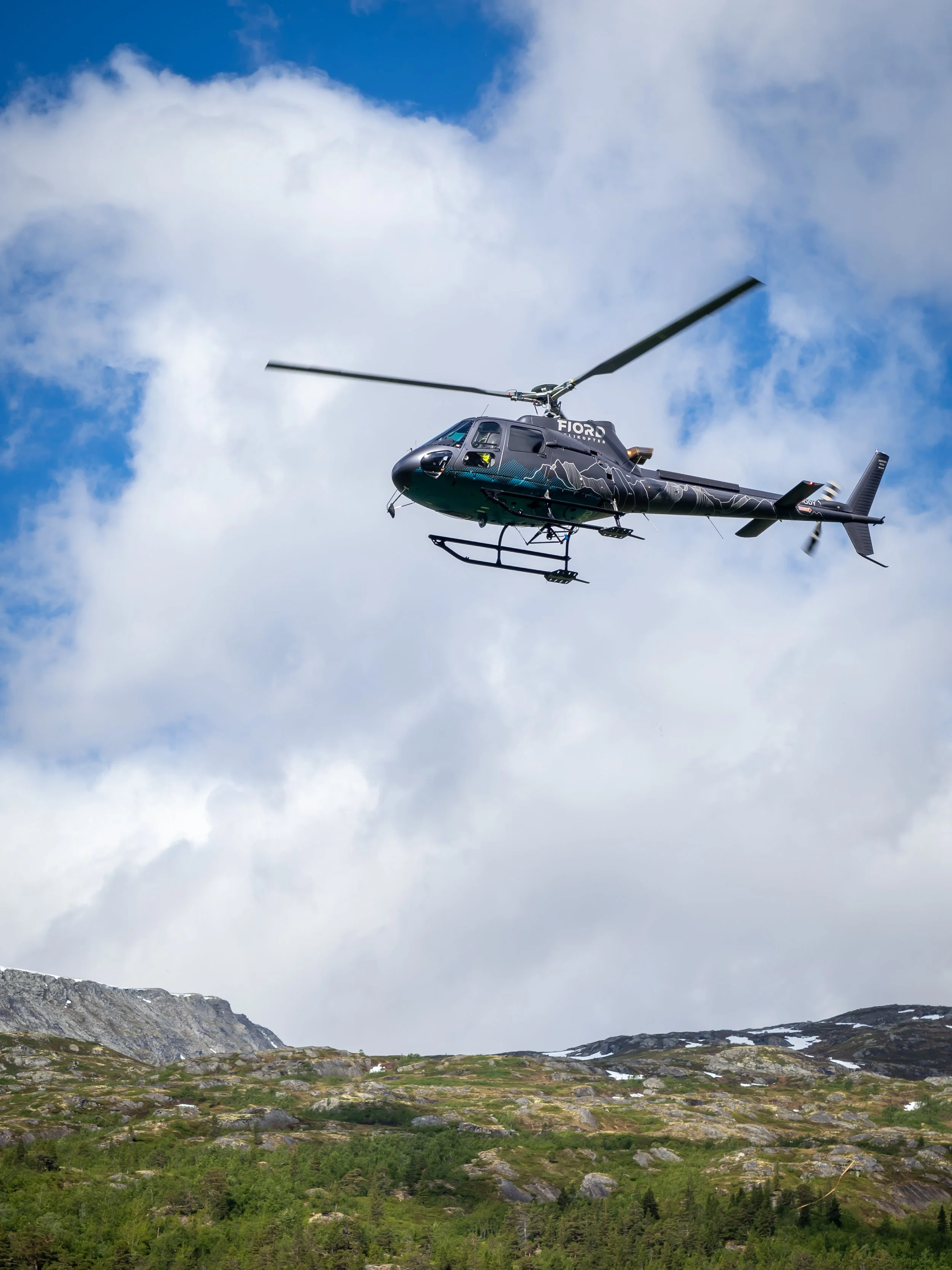 fjord helikopter logo med profilering og folieringsdesign på. helikopteret har mange fjell i designet, tegnet i hvitt og blått