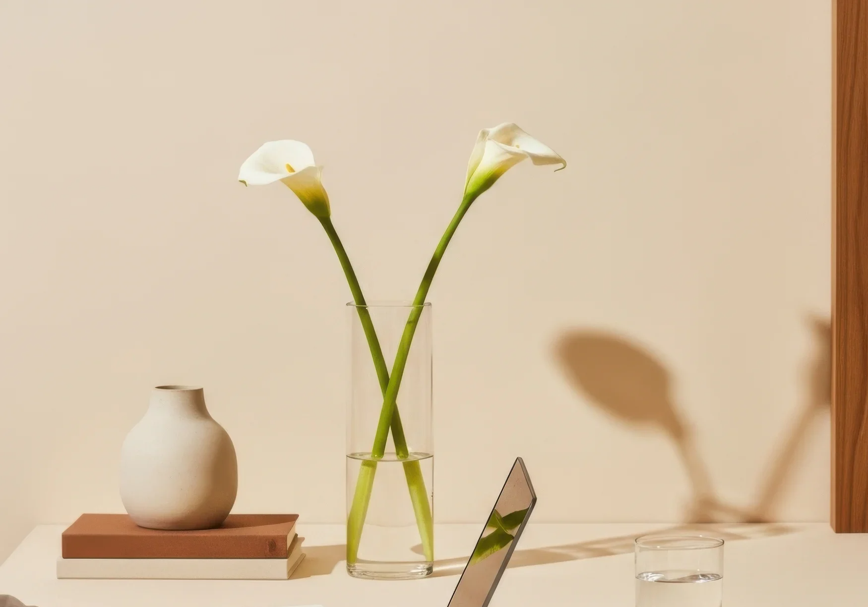 glassvase med to fredslinjer i. en keramikkvase i beige står ved siden av på 2 bruntonede bøker.