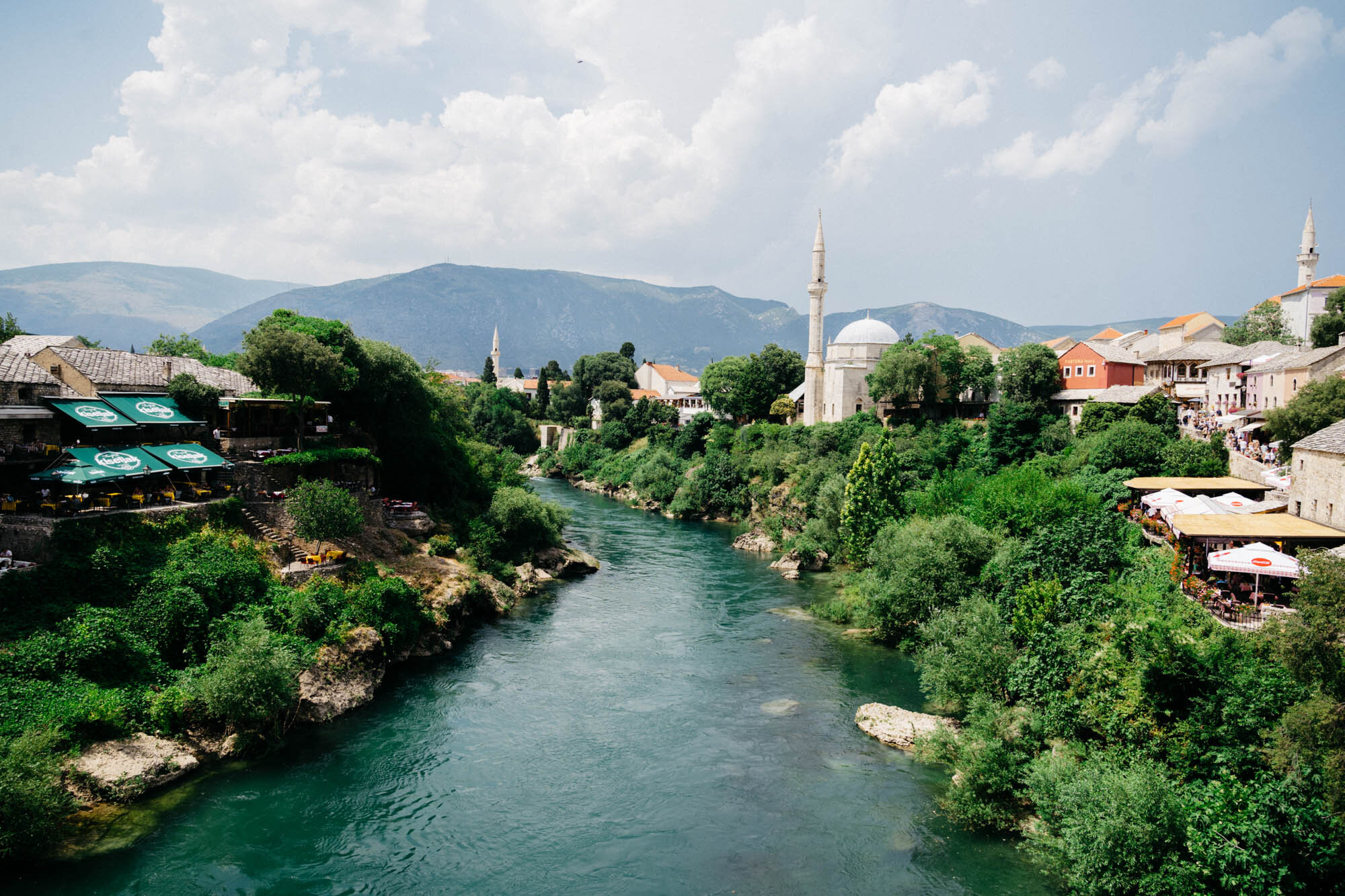  Vestiges of Ottoman architecture - like the Hadži Kurt Mosque - can be seen dotted around Mostar. They are characterised by their shallow lead domes and slim pointed minarets as seen here on the right of the river. 