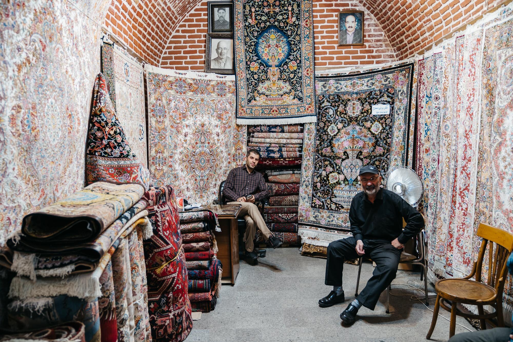  Carpet sellers. Hanging on the back wall are photographs of previous generations of those in the business. 