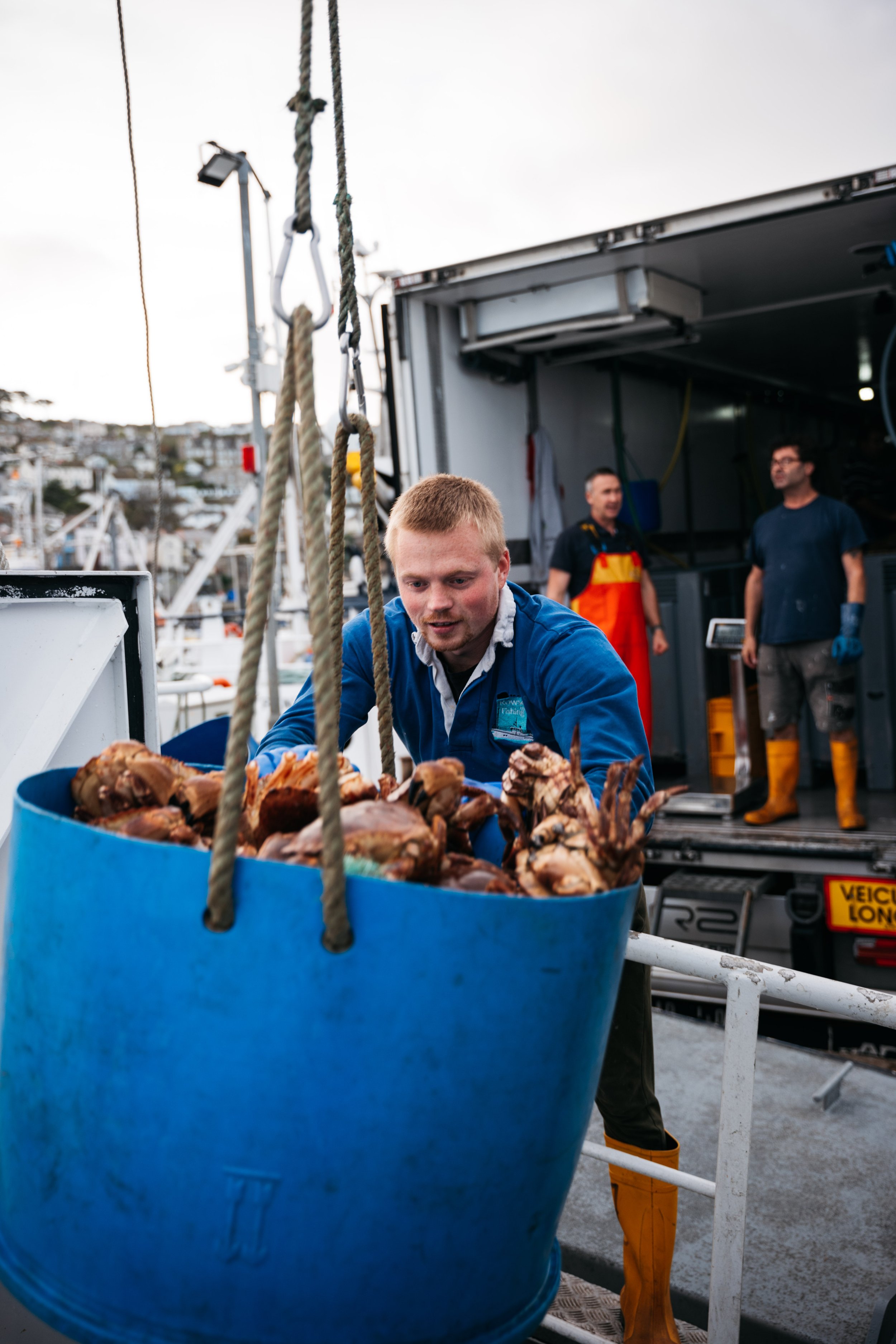  From the pier I could see large blue buckets being lowered into the hull coming up full of crab. 