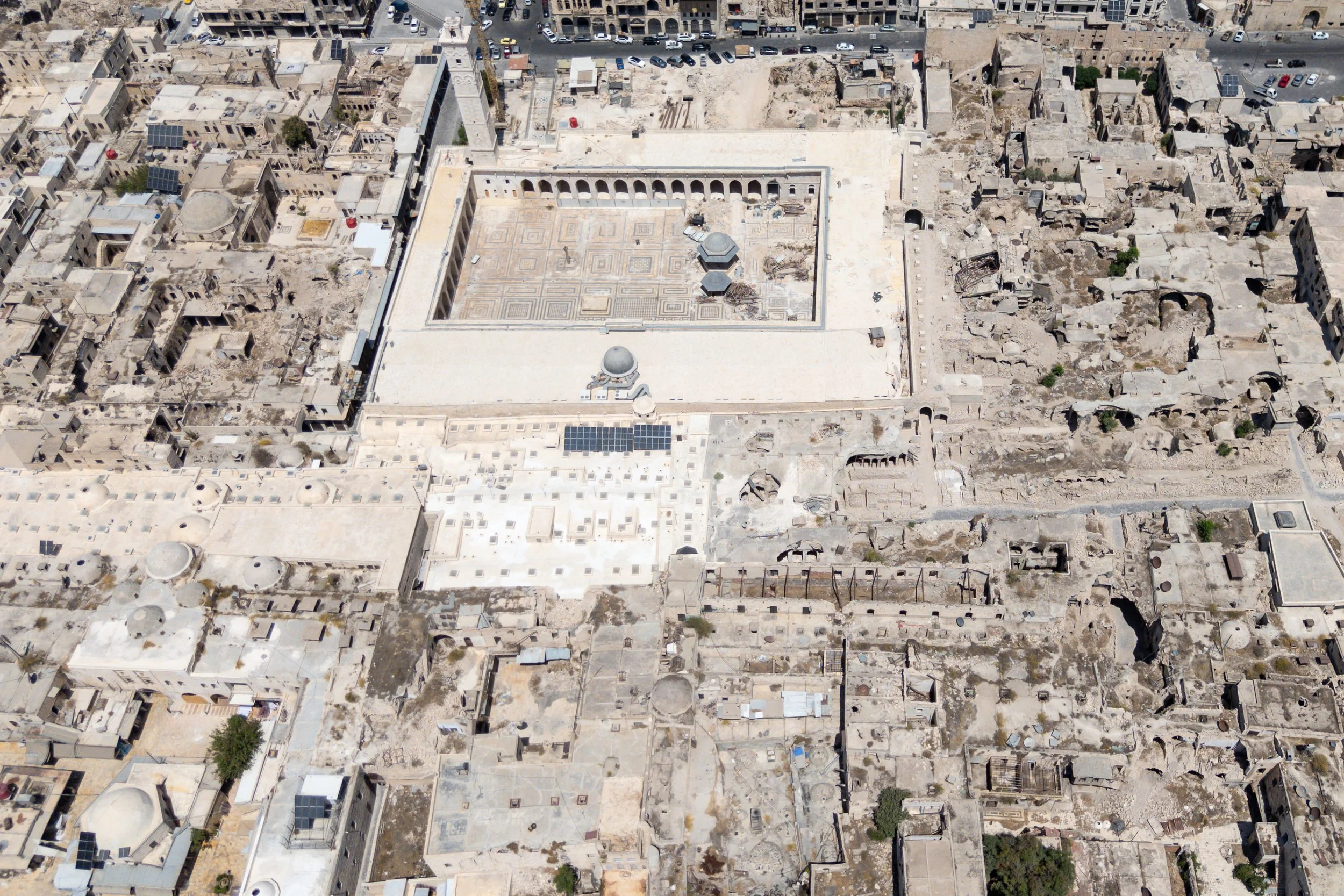  An aerial view of the Great Mosque of Aleppo. Destruction of the souk can be seen in the foreground. Sections of the souk restored by the Aga Khan Trust for Culture can be seen in the centre and left hand side; the whiter parts. 