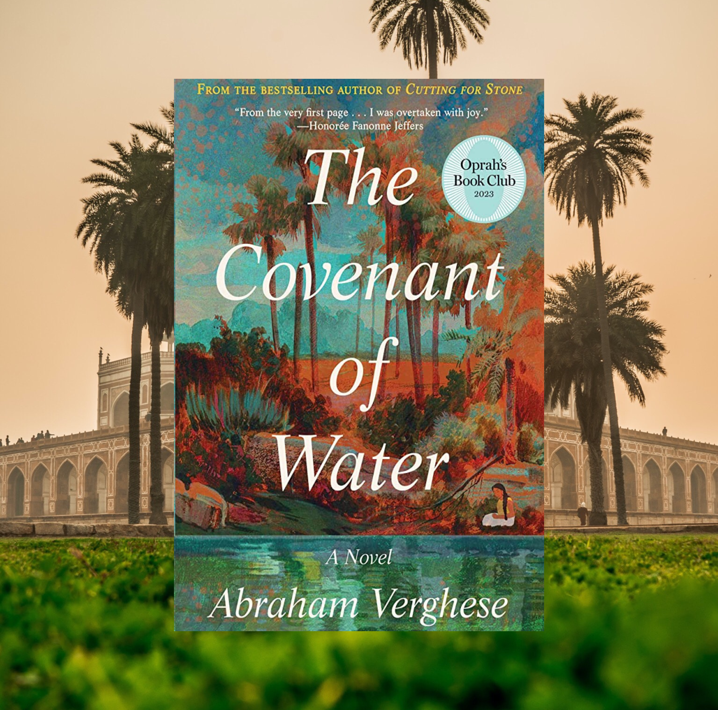 The cover of The Covenant of Water by Abraham Verghese on a background of a photo of a building in India with palm trees.