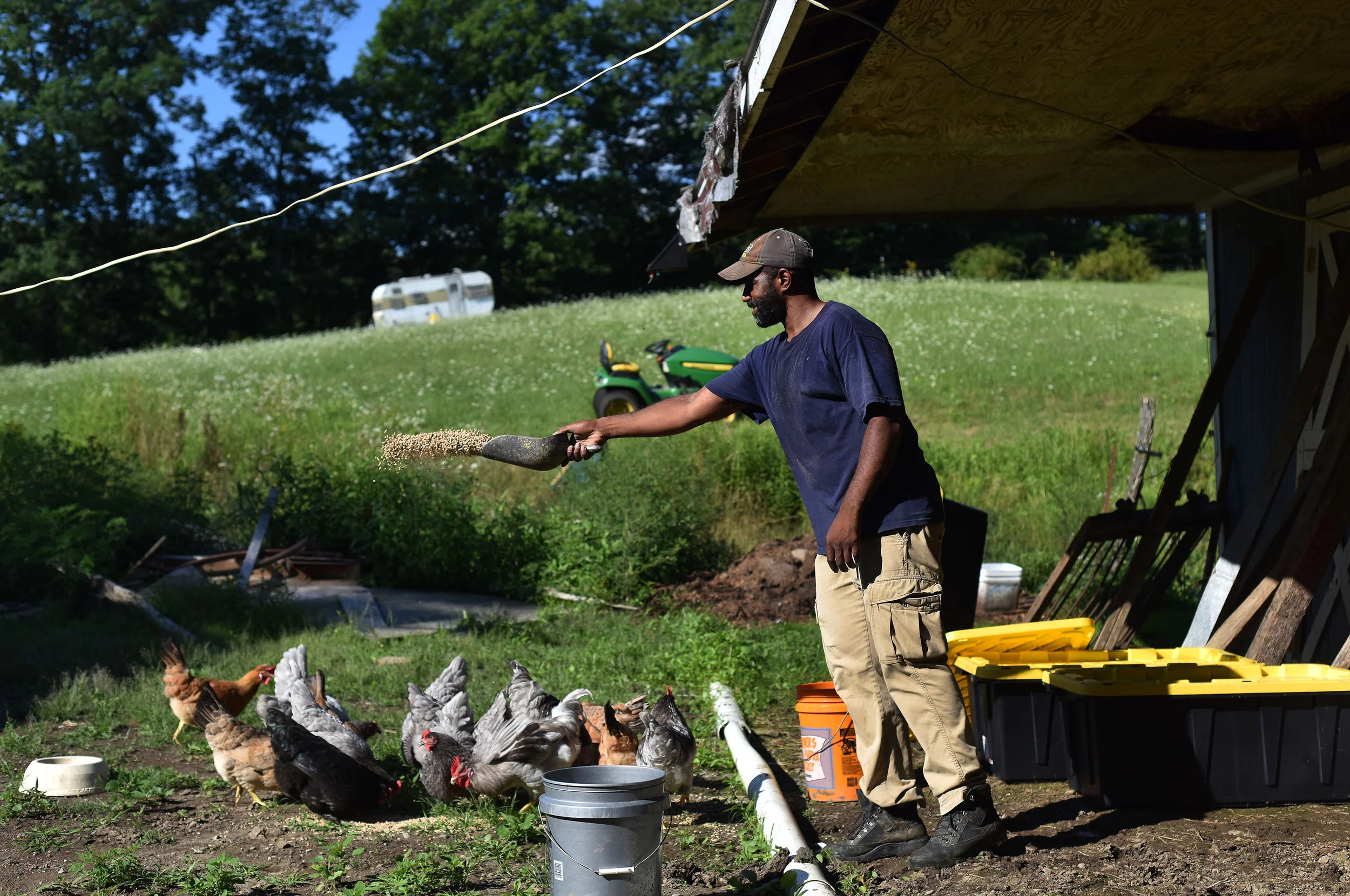 Daryl Minton, 45, throws chicken feed into a yard where the chickens roam at the Triple J Farm in Windsor, N.Y. Minton lives and works on the farm his grandfather, James Minton, bought it a decade ago. Between lending discrimination and rising costs…