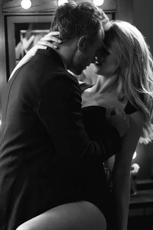 A couple is close together, touching foreheads and embracing in a black and white photo.